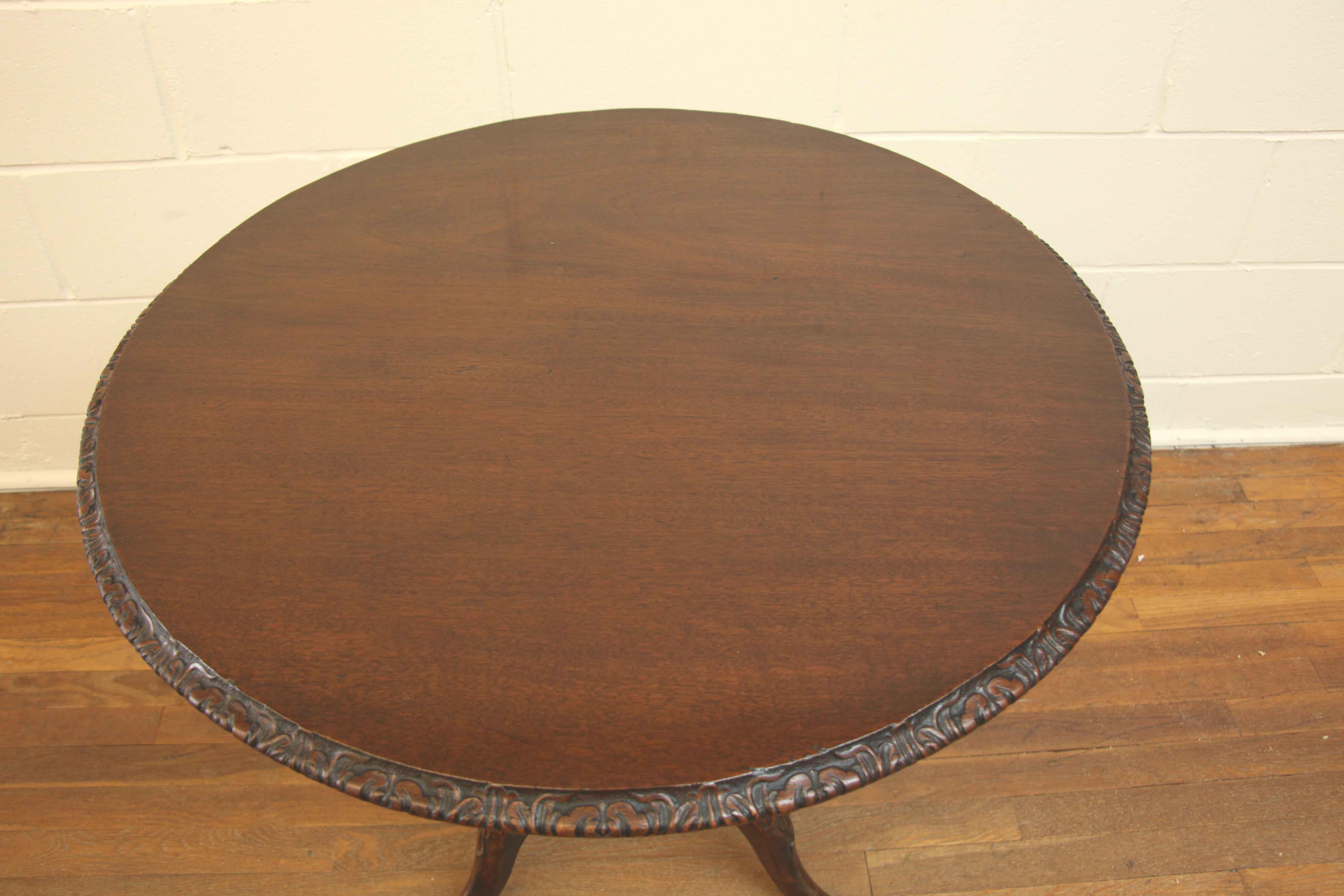 Kippbarer Tisch George III,  Die Oberseite hat eine warme, verblasste Farbe und einen kunstvoll geschnitzten Rand, der Mittelschaft ist mit Balustern gedreht und an der Basis geschnitzt.  Oben auf den Beinen befindet sich eine geschnitzte Kartusche