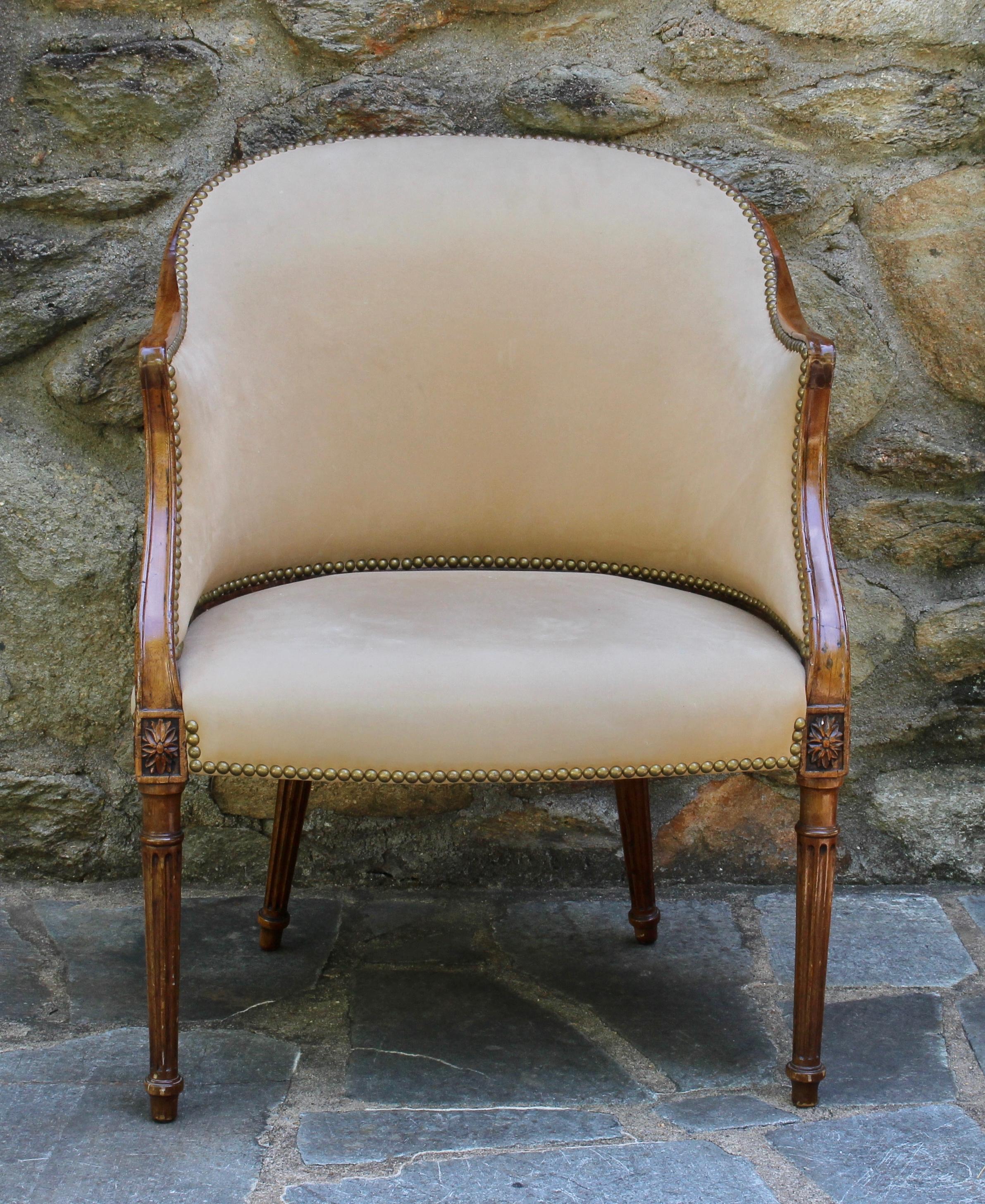 A late 18th century English carved elmwood barrel-backed bergere in the French taste recently upholstered in a nubuck suede accented with brass tacks.