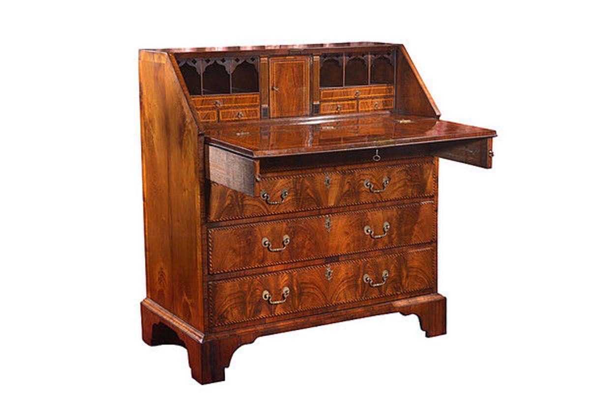A well figured George III walnut and feather banded bureau. 
The fall front with pull supports, opens to reveal a fitted interior consisting of a central door and to each side, a secret pull-out compartment, three cubby holes with arched fretwork