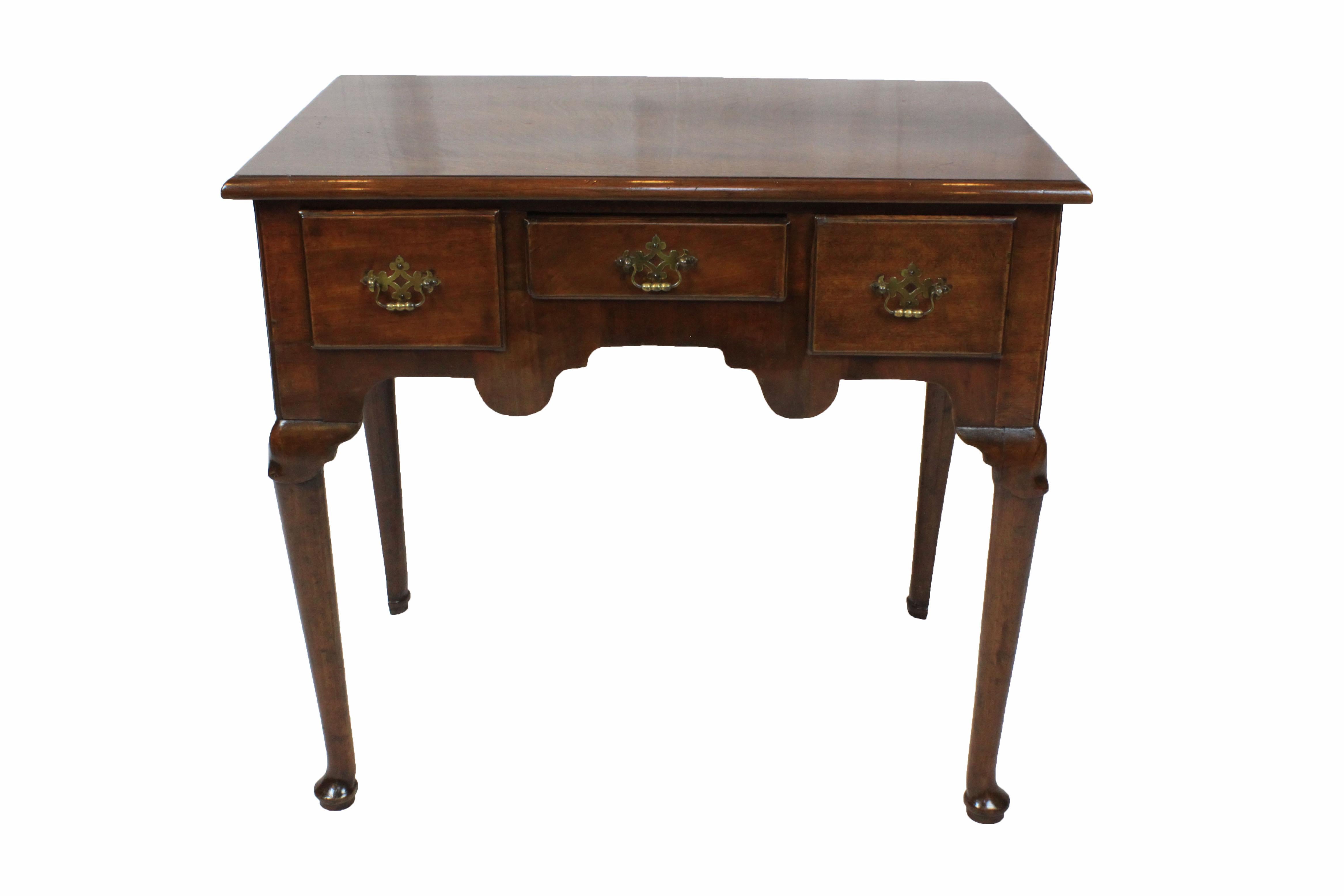 George III walnut lowboy with solid top, standing on straight Queen Anne legs with carved poleyn style knees and ending in pad feet. Unusually shaped rear legs.