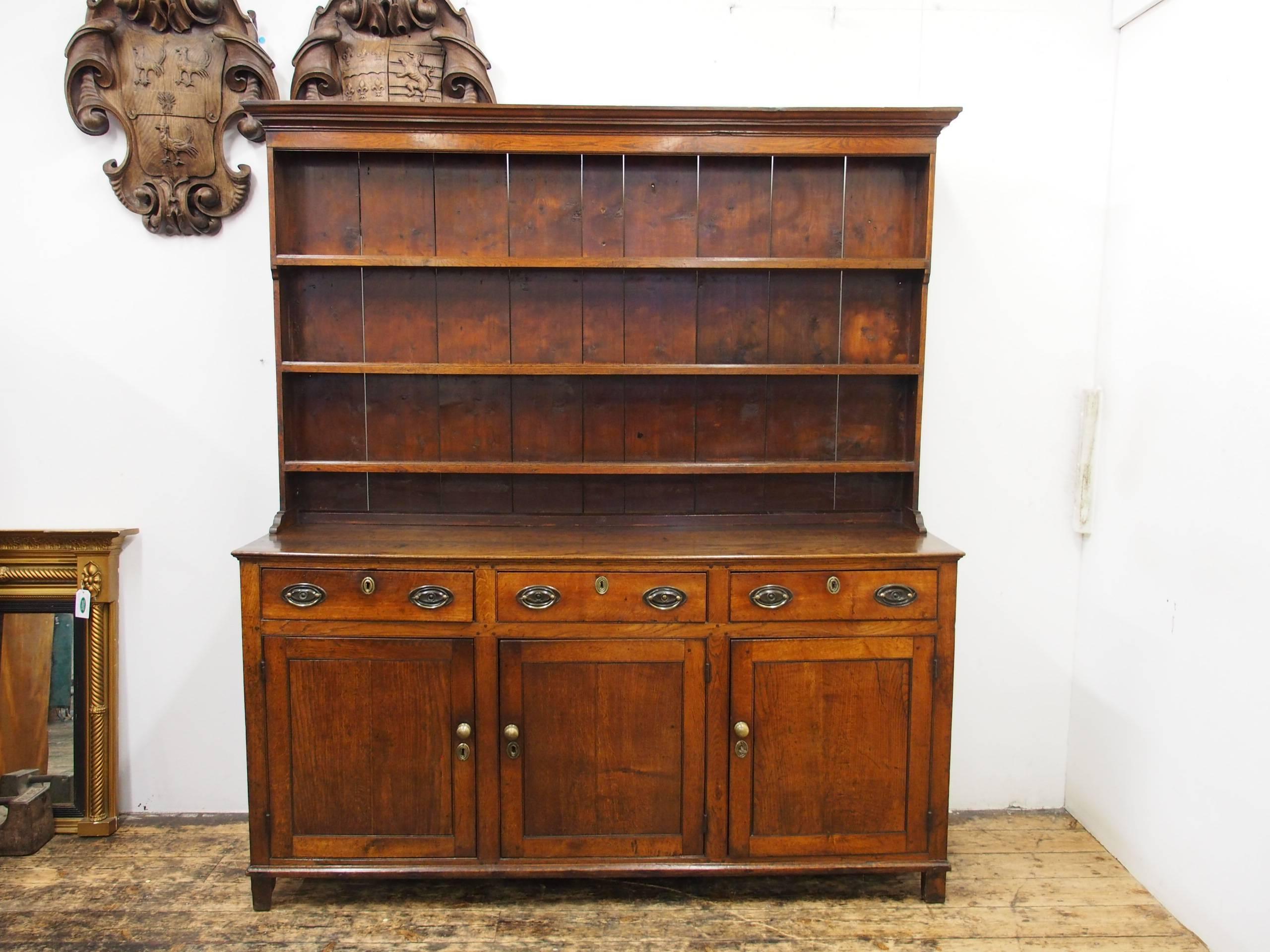 George III Welsh oak dresser, circa 1800. There is an original rack with a protruding moulded cornice and it retains its original vertical backboards with three grooved shelves. The base has a three plank top which is over three frieze drawers with