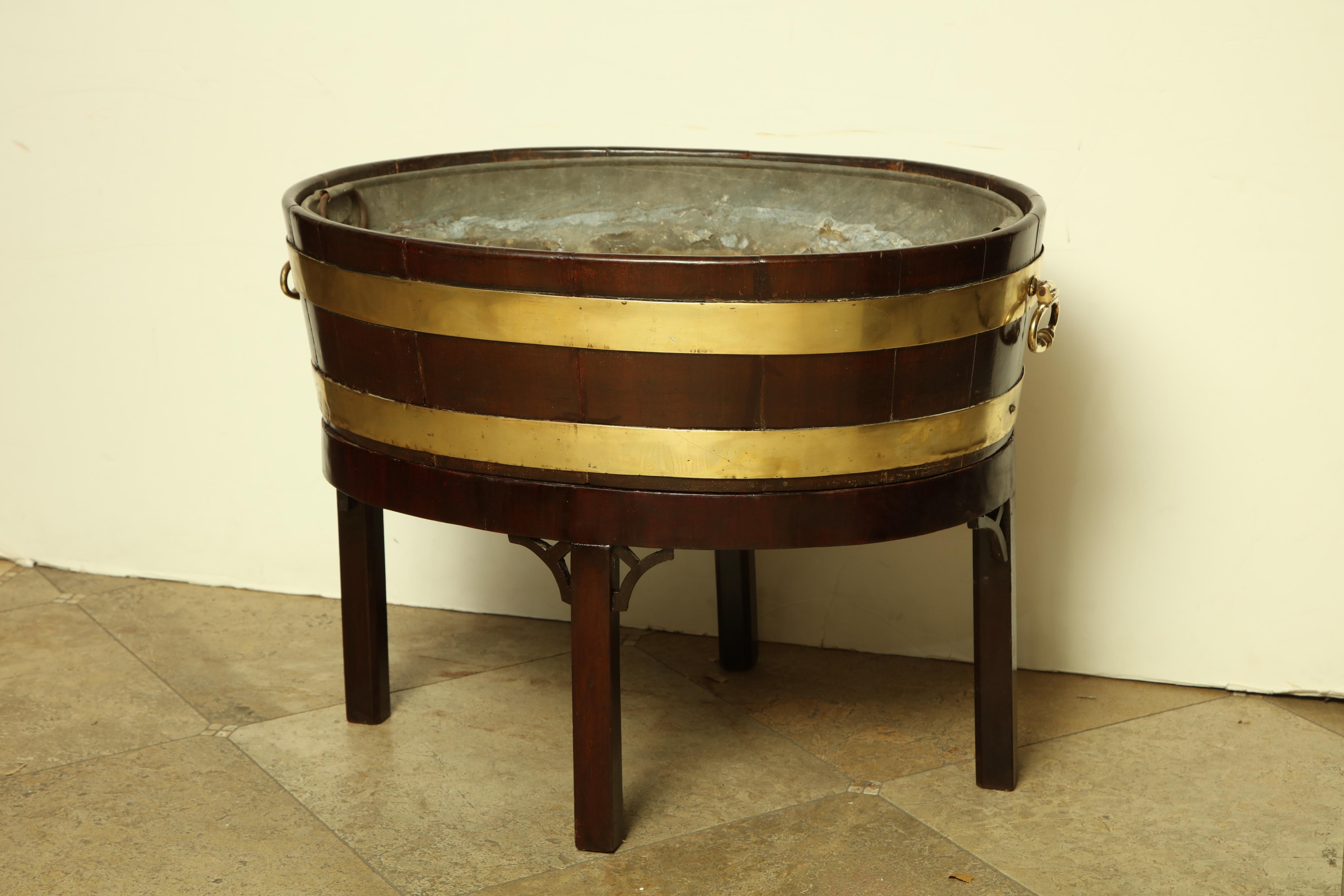 George III mahogany brass bound oval wine cooler cellarette with liner, brass handles and raised on mahogany base.