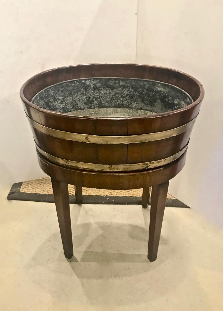 This is a Classic George III double brass banded mahogany wine cooler. The cooler is in overall good unrestored condition showing normal shrinkage for its 200+ years of life. As shown in the photos, the lip of the Stand shows two areas of loss which