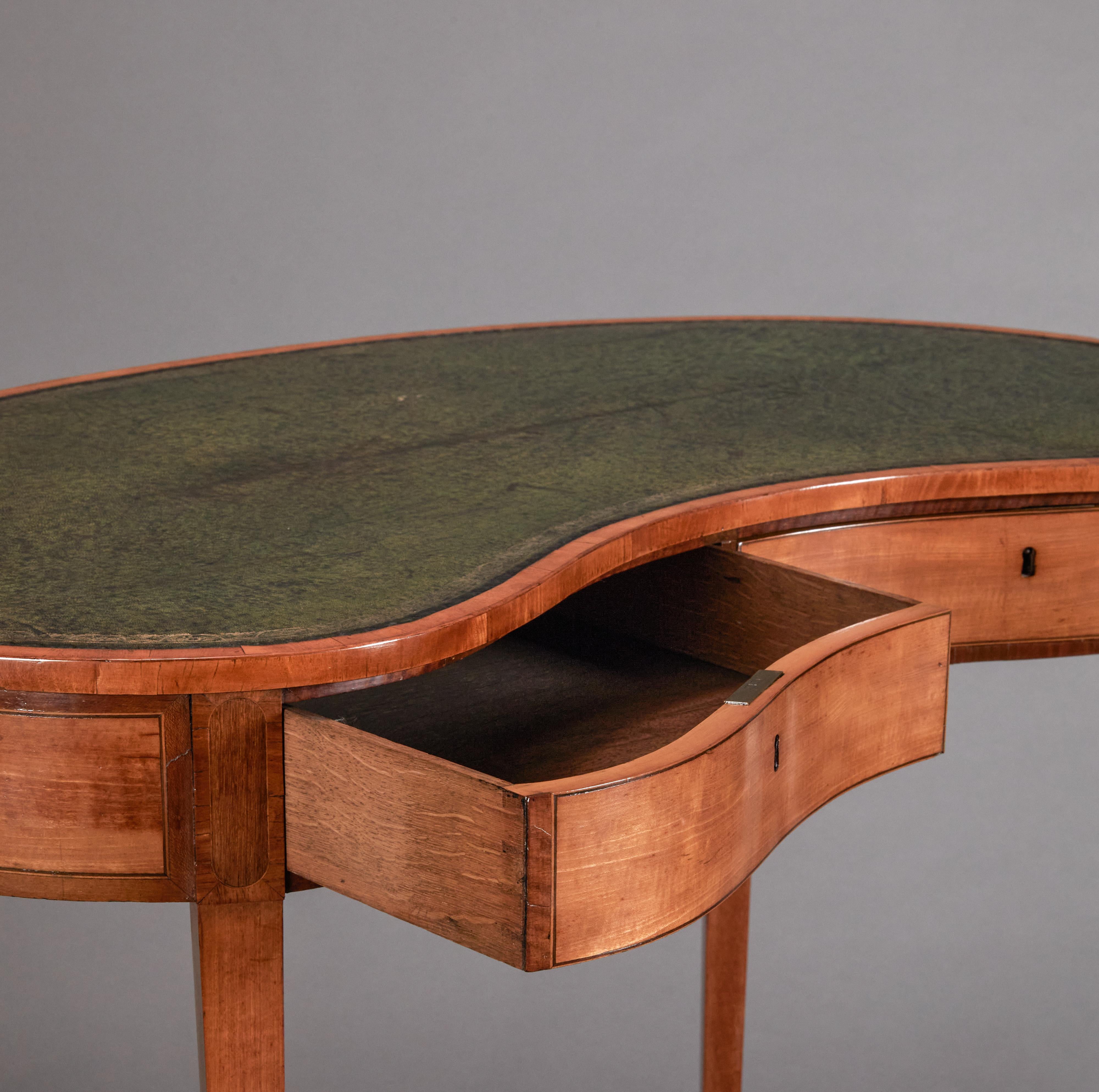 Satinwood and tulipwood veneered kidney shaped writing table. Beautifully patinaed green leather top with embossed gold trim.