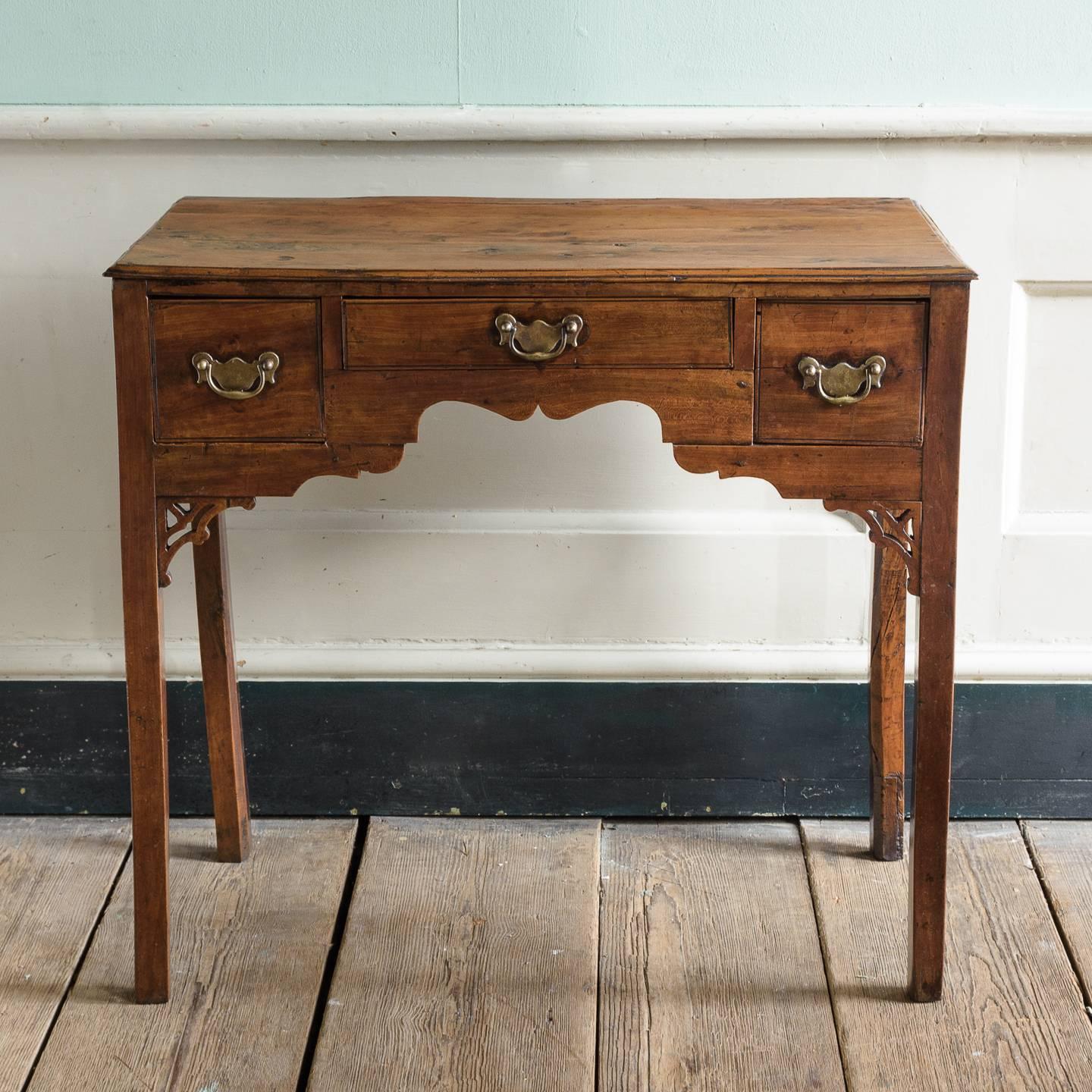 A George III yew wood and cherrywood lowboy with three drawers above Cupid’s bow frieze with fret cut brackets.

Yew is a native timber which was highly prized by cabinet makers in the eighteenth century and often used for the finest country-made