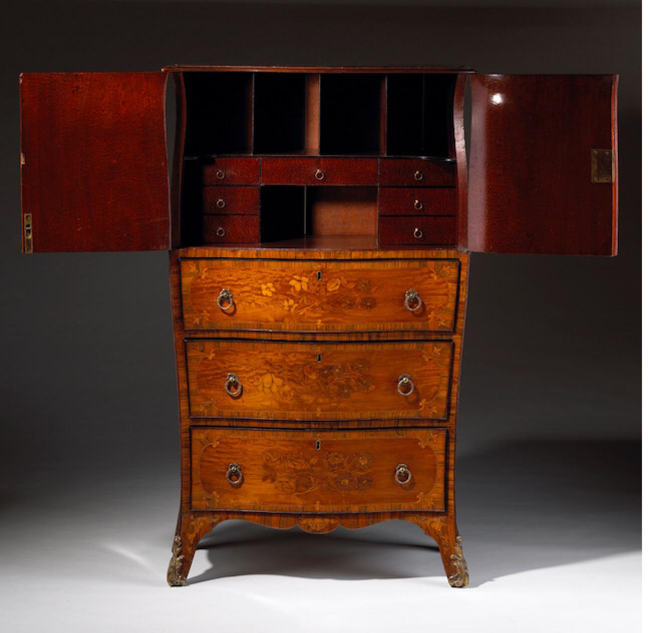 A charming George III yew wood, satinwood and floral marquetry bombe secretaire cabinet circa 1770 attributed to Ince and Mayhew. The shaped top has elegant eared corners above a pair of cupboard doors enclosing a neat writing surface and an