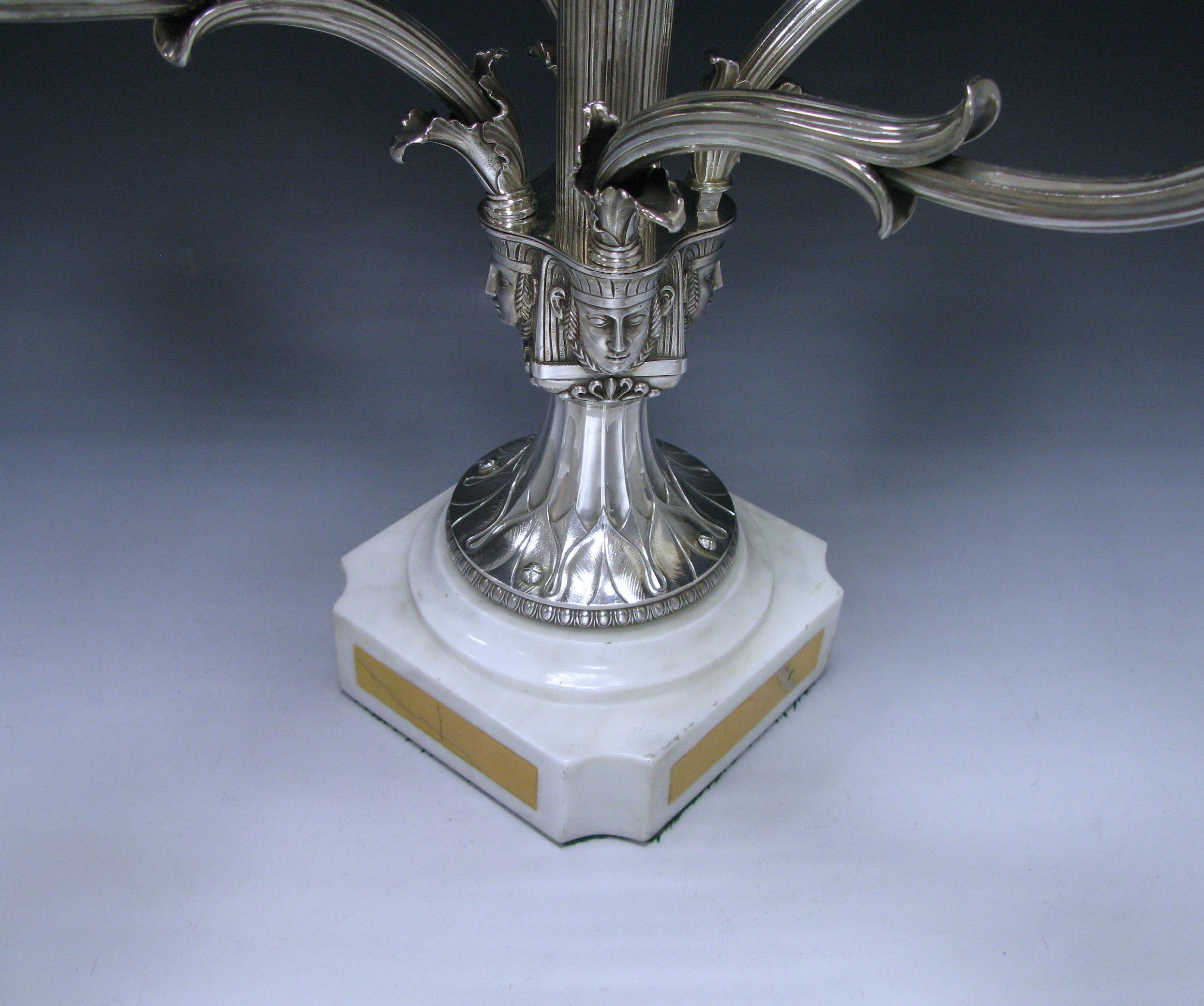 A George IV antique silver epergne centerpiece, having a central bowl for sweets or fruit and four braches for candlesticks. The centrepiece stands on a marble base. The central column emerges from four Egyptian heads which in turn, the removable