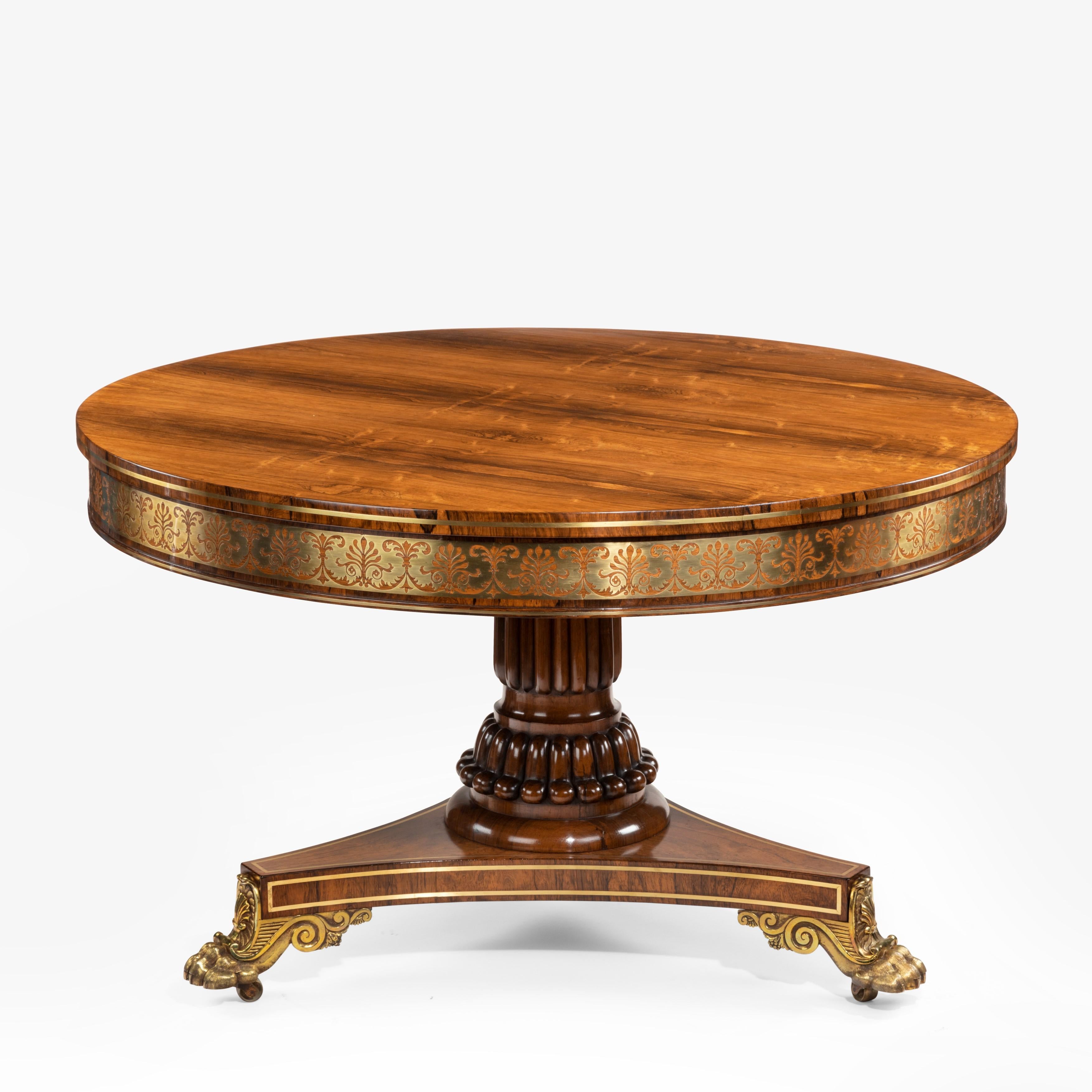 A fine George IV brass-inlaid rosewood centre table attributed to Gillows, the circular tilt-top with beautifully matched veneers, decorated with a continuous brass frieze of contre-partie anthemion and scroll-leaf and brass stringing, all set on a