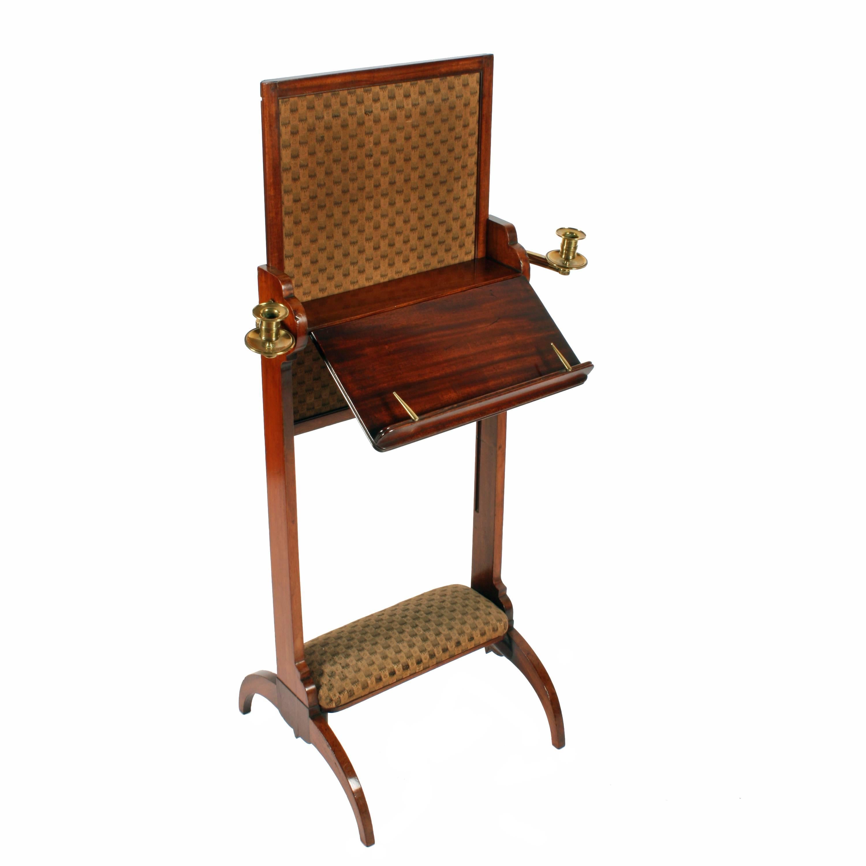 George IV mahogany adjustable combined music stand, fire screen and foot rest, circa 1820. With adjustable, mahogany framed fabric section to the back and two adjustable candle holders in brass and polished shelf top. The music stand has a small