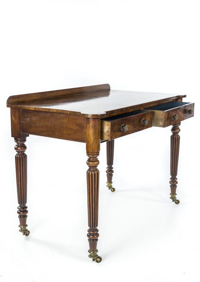 A George IV figured mahogany side or writing table attributed to Gillows, the cross banded top over two drawers on turned and reeeded tapering legs to brass caps and castors

Gillows of Lancaster and London, also known as Gillow & Co., was an