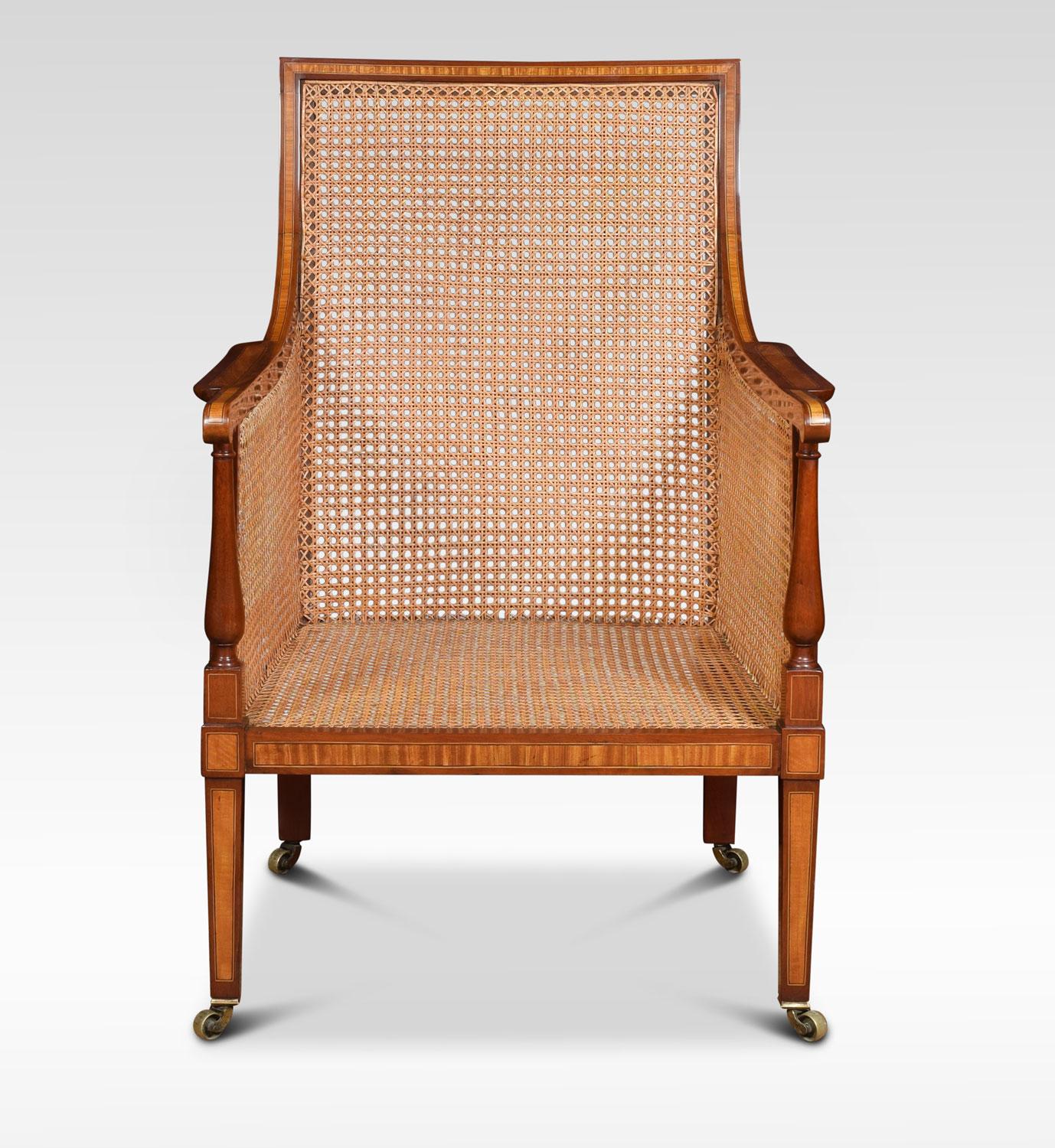 19th century bergère armchair, the solid mahogany frame having satinwood inlay throughout. The inset bergere back and seat with removable black leather cushion. Raised up on tapering front legs terminating in brass castors
Dimensions:
Height 39.5