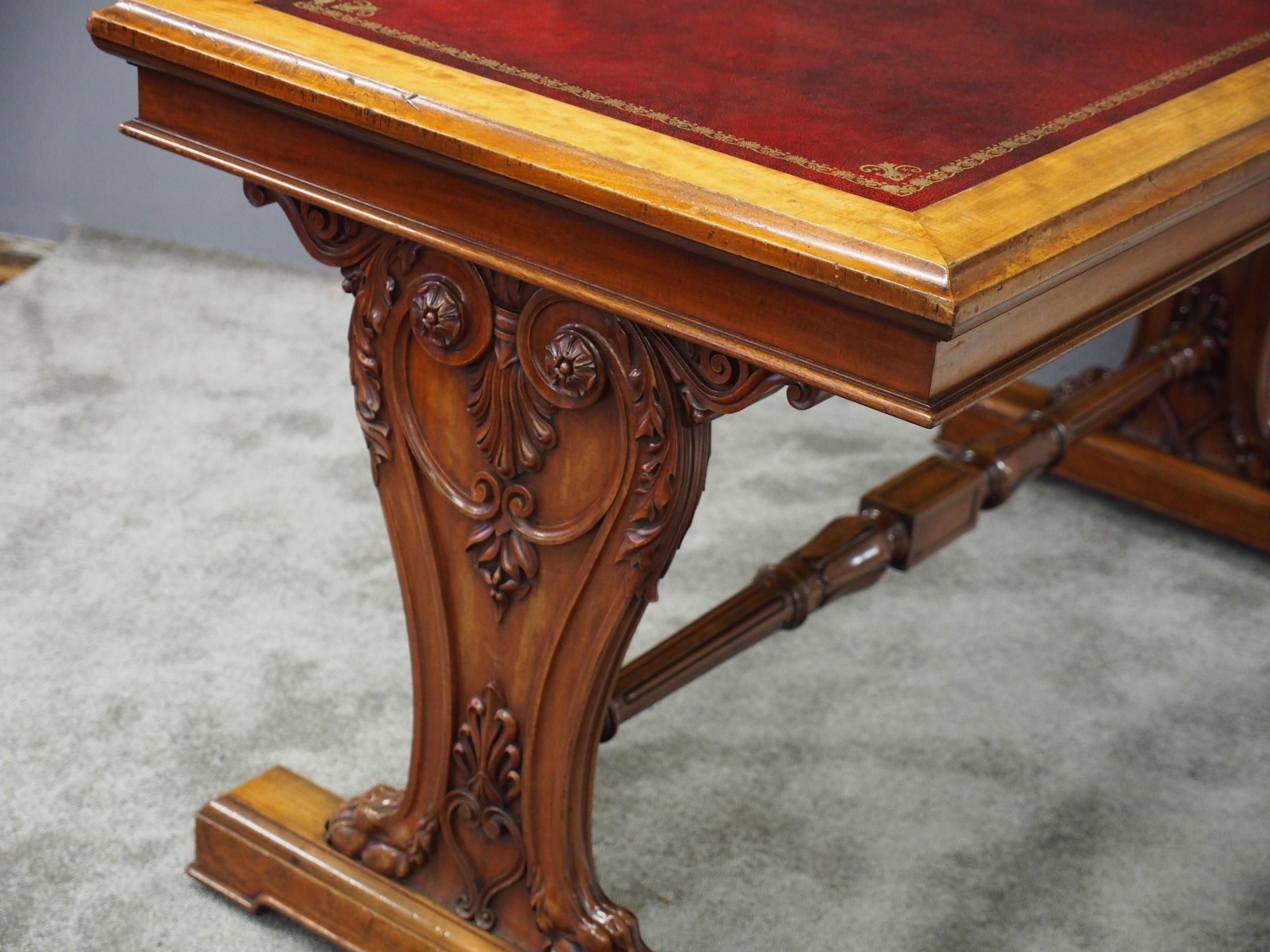 Freestanding George IV mahogany library table, circa 1830. The rectangular top with thumb-moulded edge and new gilt-tooled red leather writing surface over a narrow beaded frieze. This is supported on Renaissance style trestles with deeply carved