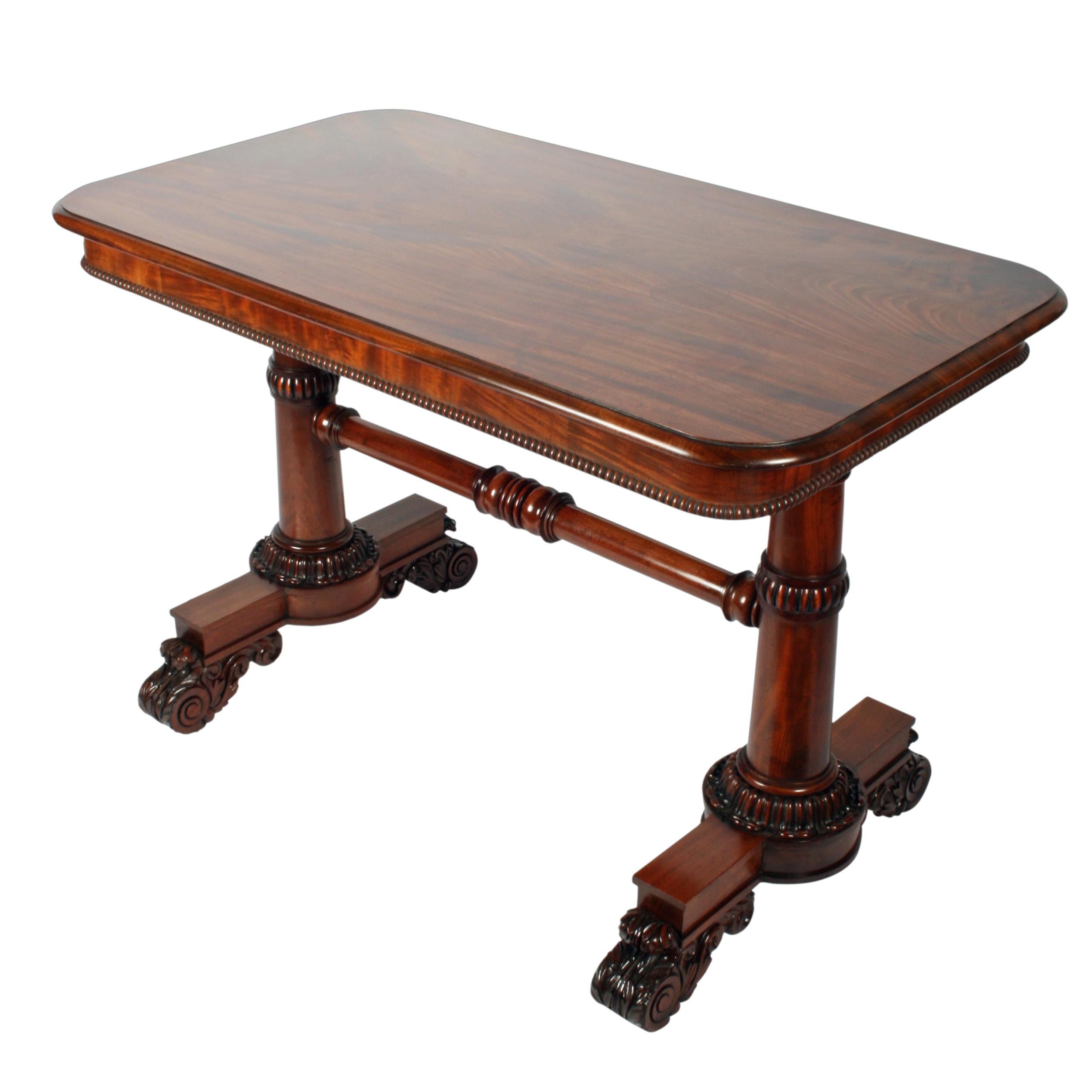 An early 19th century George IV mahogany library table.

The table has twin platform bases with concealed casters and a one piece mahogany top that has a shallow frieze and a pea beaded edge.

The platform supports are raised on carved scrolling