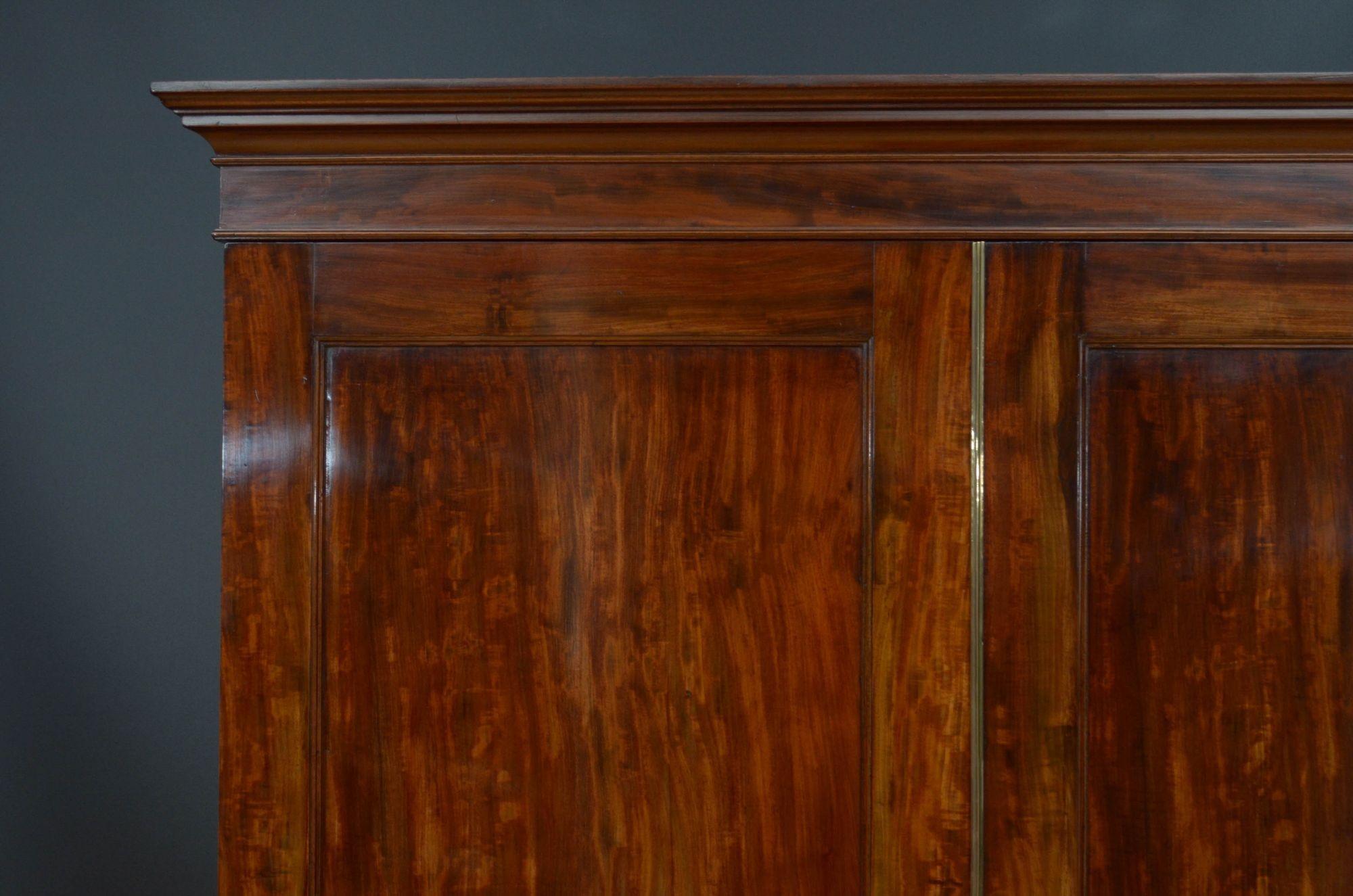St030 Fine quality Georgian two door wardrobe in mahogany, having cavetto cornice above a shallow frieze and a pair of panelled, figured mahogany door fitted with original working lock and a kay and brass centre bead, enclosing newly lined interior