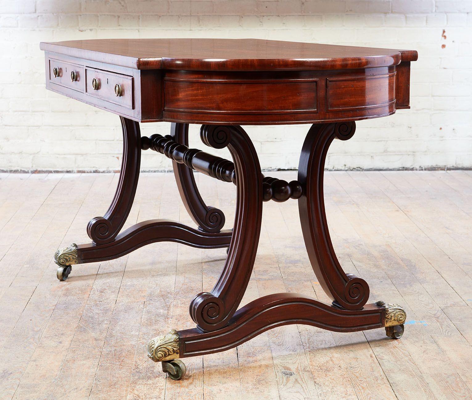 Fine George IV period mahogany library/writing table, the tablet-shaped top in dense, rich mahogany over two working and two false (one each side) drawers standing on curule molded supports and legs ending in foliate cast toe caps and original brass