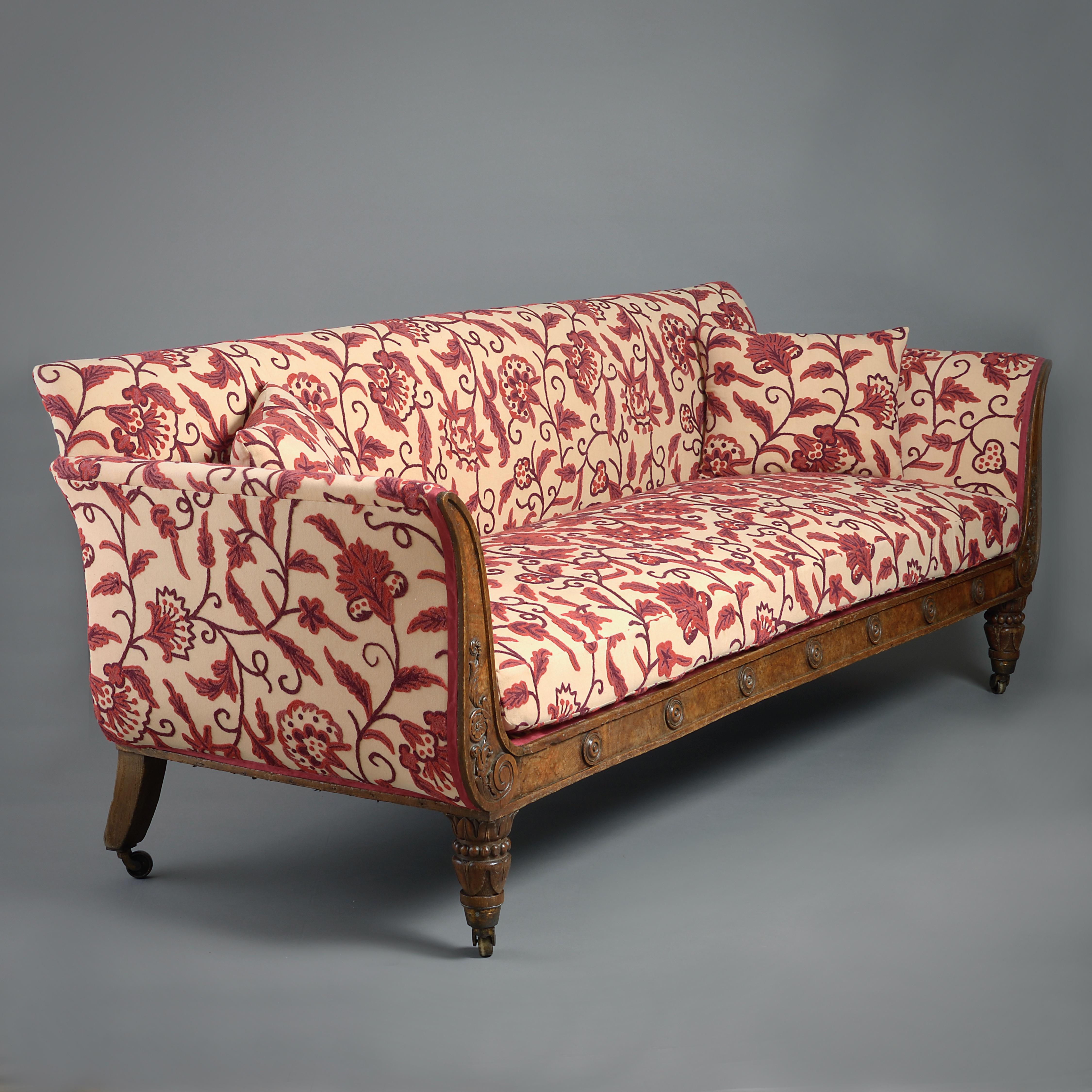 A FINE GEORGE IV POLLARD OAK SOFA UPHOLSTERED IN CREWEL WORK, CIRCA 1830.

The frame carved with foliage and applied with turned roundels.