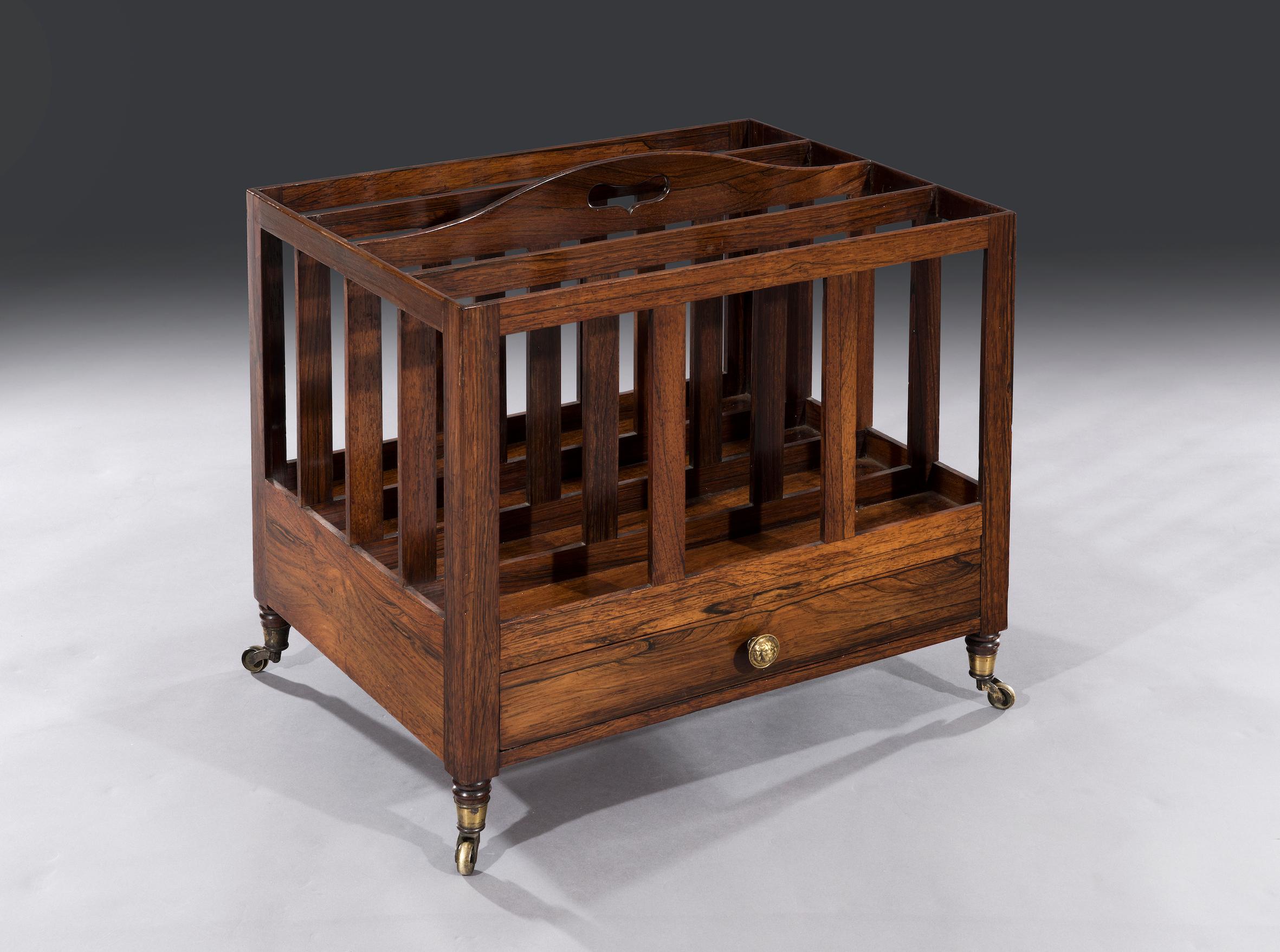 The Regency rosewood Canterbury has four divisions and a carved carrying handle with solid rosewood uprights, above a full length mahogany lined drawer. The Canterbury stands on its original castors.