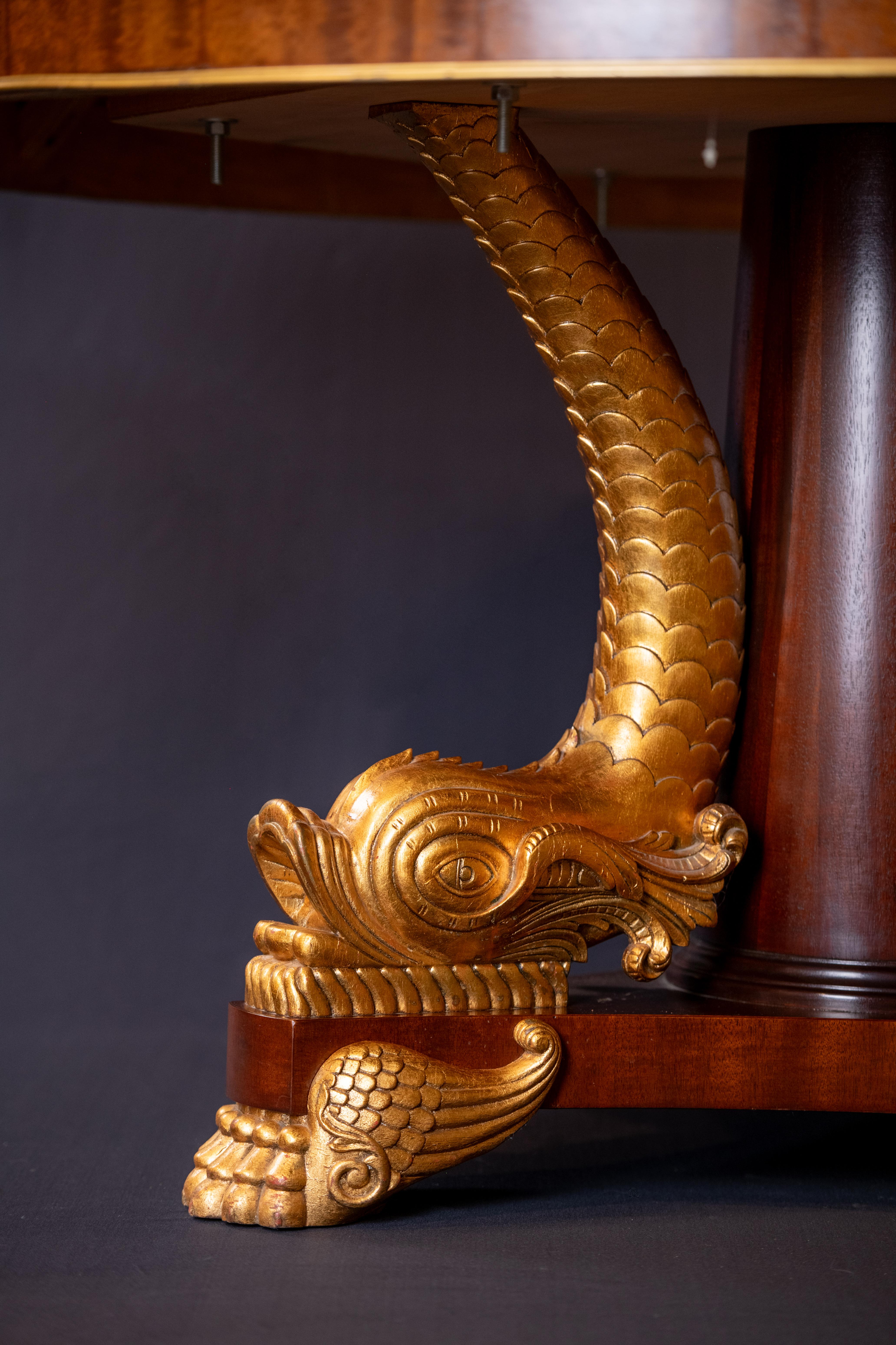 George IV Regency style, large round dining or huge center table with Dolphin gilded base.  The base is solid hand carved wood with giltwood Dolphins as pedestals., The top is very large flamed mahogany with gilt banding.  The apron is approximately