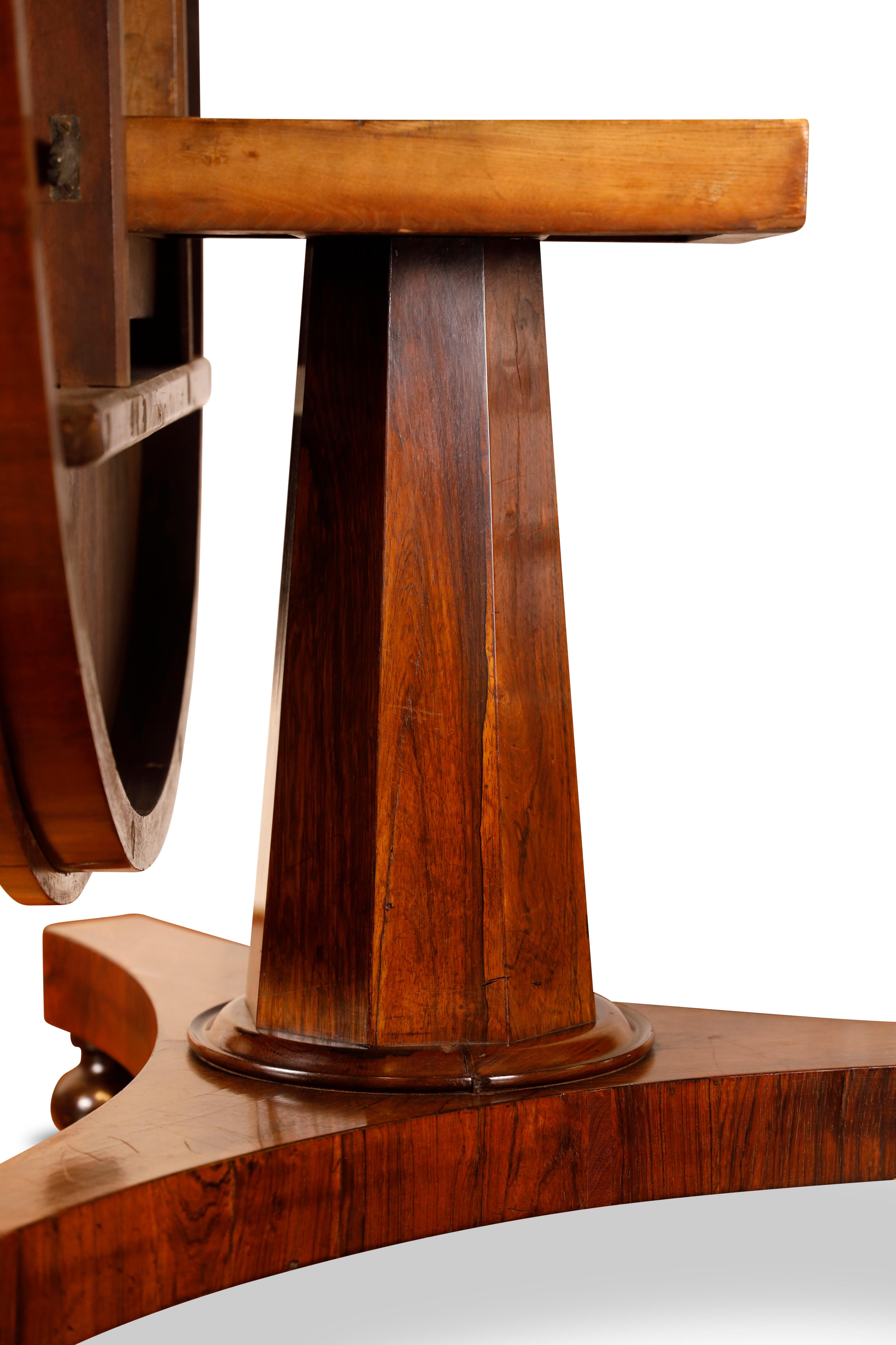 George IV rosewood circular center table with tapering octagonal column ending in triped platform base raised on bun feet with hidden casters.  Table tilts up.