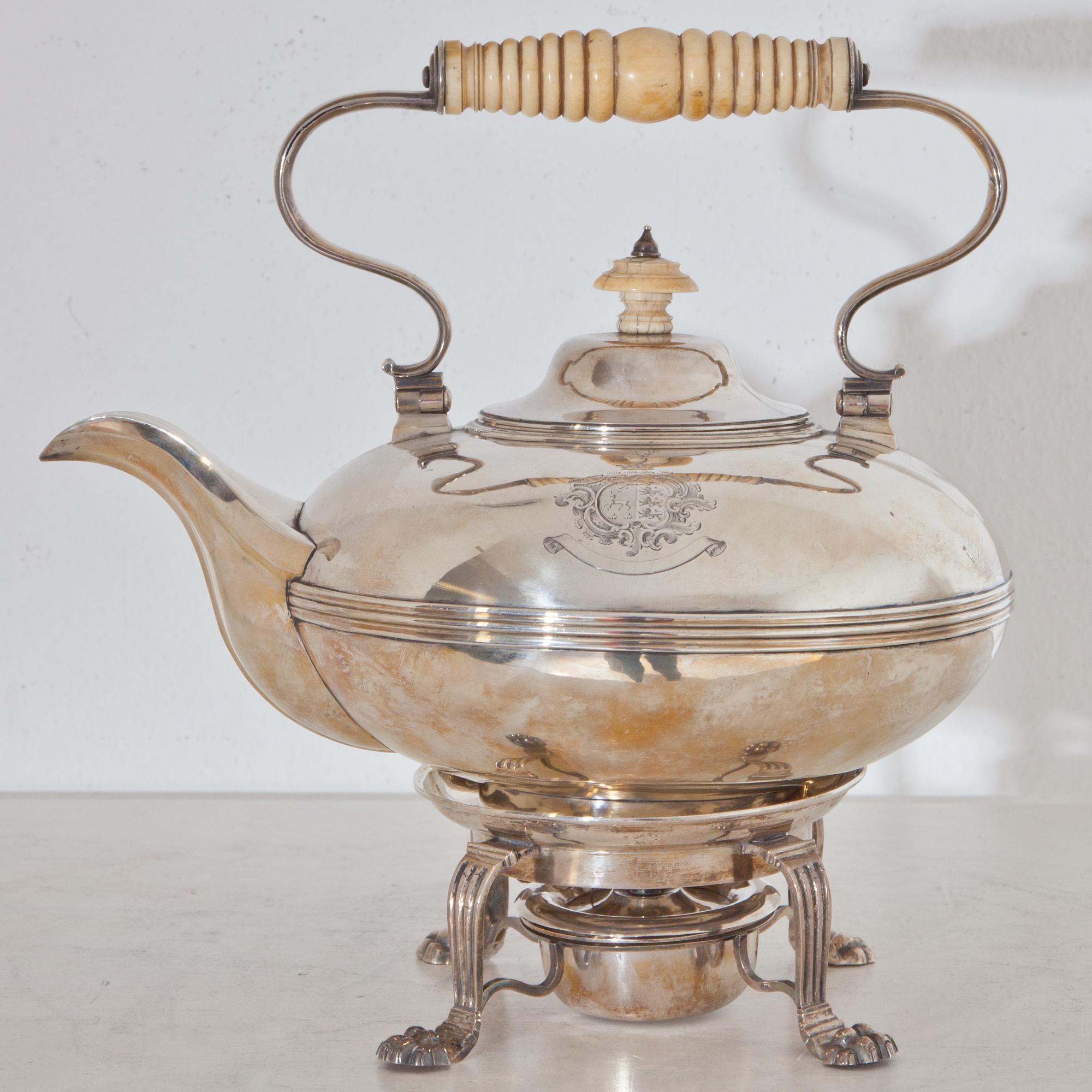 Irish teapot made of sterling silver by William Nolan, marked Dublin 1828-29 and a warmer on lion paw feet. Engraved coat of arms on the wall of the O'Connell family (stag between three trefoils) impaling Carew family (three lions), possibly at the