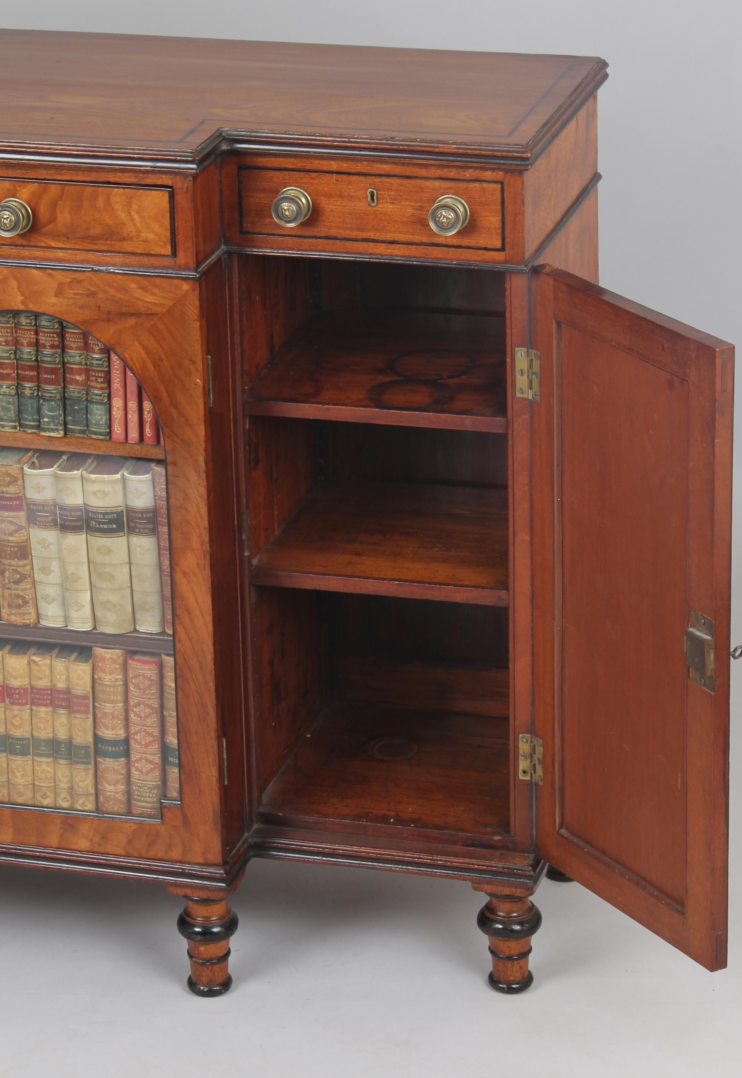 George IV small mahogany breakfront side-cabinet; the central cupboard with two adjustable shelves enclosed by doors with arched glazing, flanked by narrow cupboards with panelled doors; the frieze with a drawer fitted with a hinged writing-flap, a