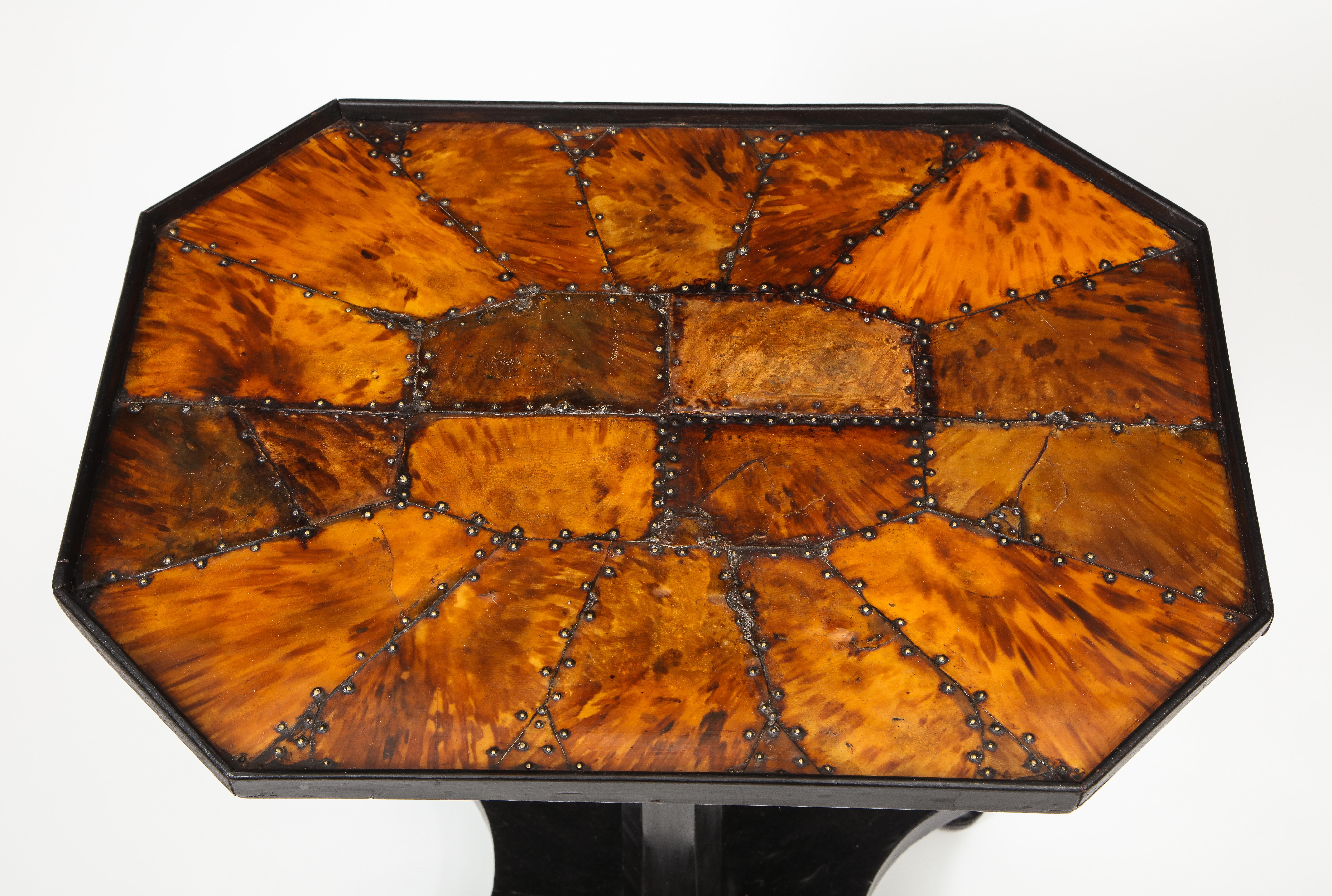 The octagonal top inlaid with tortoiseshell and flame mahogany secured by metal studs; raised on an ebonized chamfered columnar support on a quadripartite base on turned feet.