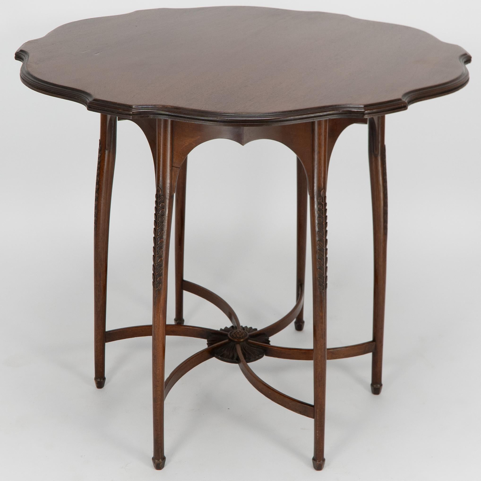 George Jack for Morris and Co. A high Aesthetic Movement circular side table with a shaped top and shaped upper apron standing on six beautifully shaped legs, each with fine carved floral decoration growing up the outer edges, the lower legs united