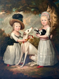 Portrait of two young girls with a whippet and a rabbit in a wooded landscape
