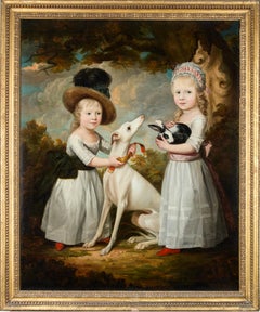 Portrait of two young girls with a whippet and a rabbit in a wooded landscape
