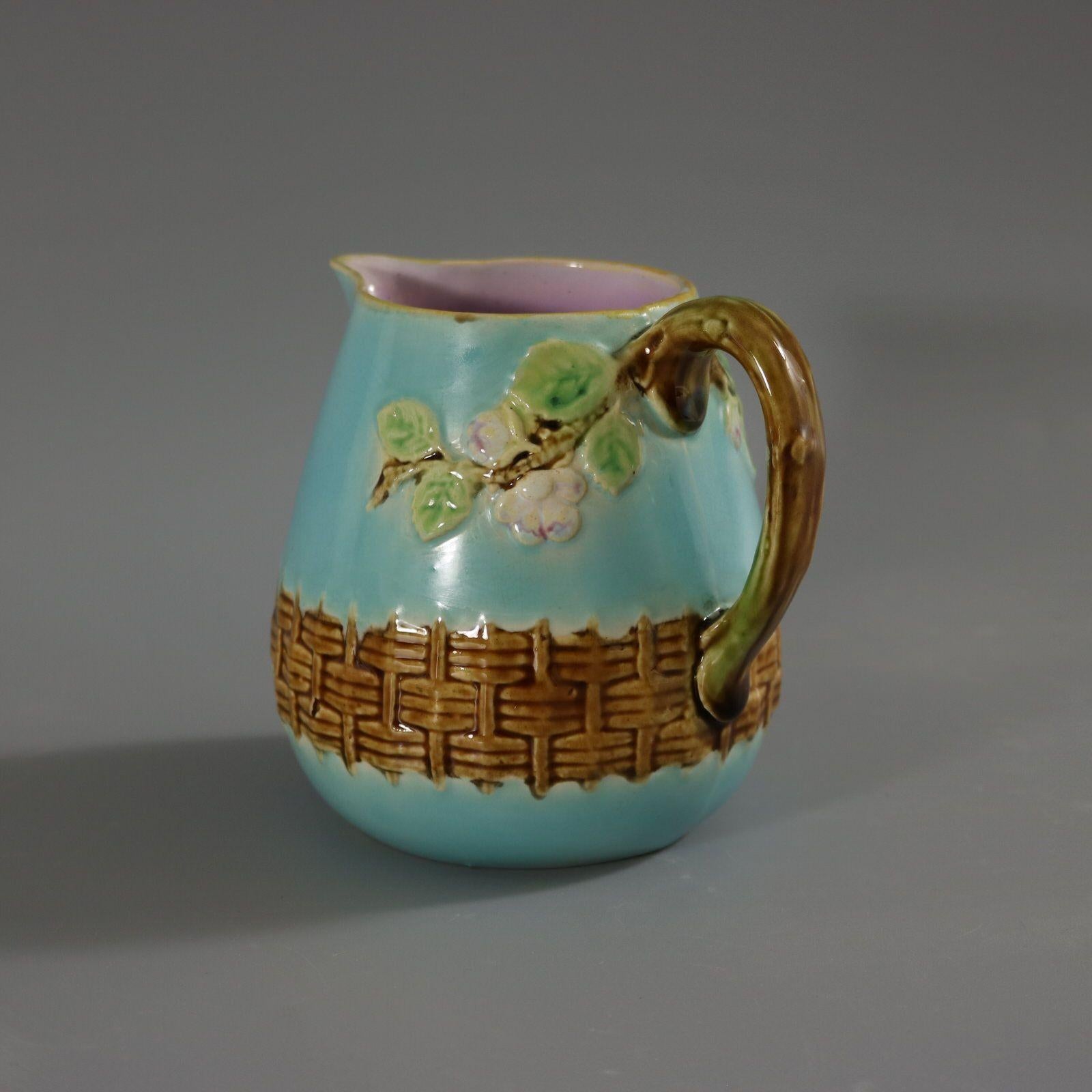 George Jones Majolica jug/creamer which features a branch handle, with blossom branching off on either side and a basket weave border to bottom. Colouration: turquoise, brown, green, are predominant. Bears a pattern number, '3304'. Part of a teaset.