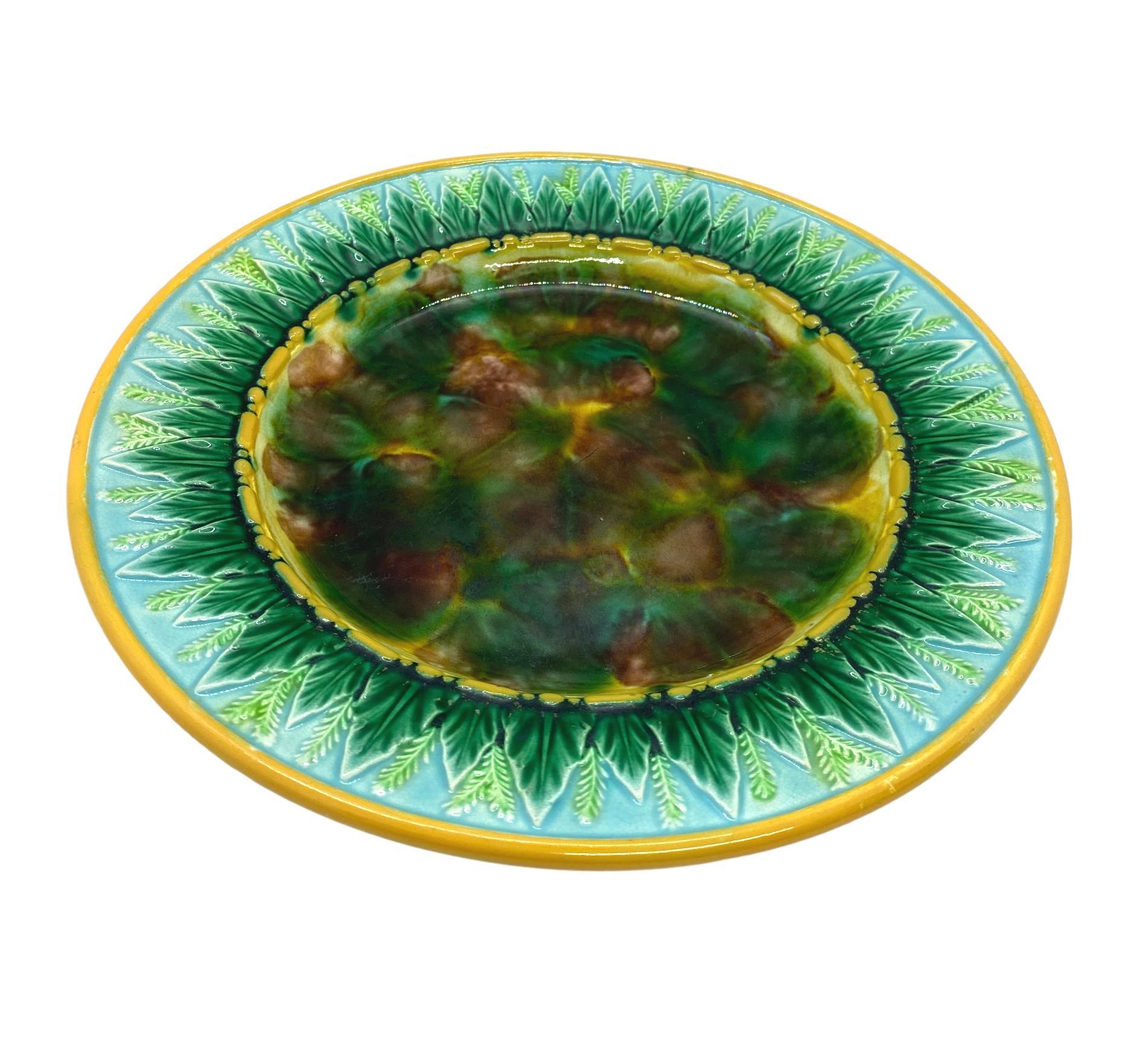 George Jones Majolica 9-in plate with mottled center, green wheat leaves and wheat stalks on turquoise, the inner and outer border glazed in yellow or ochre. The reverse with impressed 'GJ' monogram and painted pattern number '1808,' English, circa