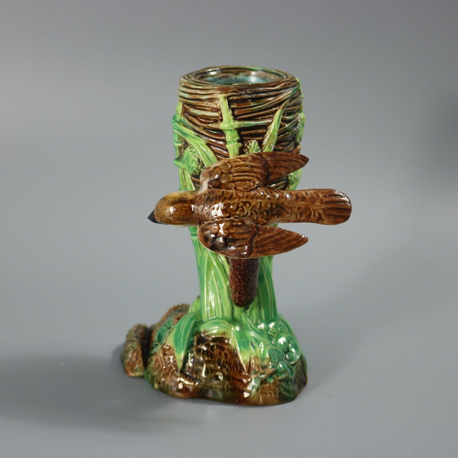 Vase porte-menu en majolique de George Jones représentant un oiseau (fauvette) perché au sommet d'un jonc à côté de son nid. Coloration : brun, vert, blanc, sont prédominants. La pièce porte les marques du fabricant de la poterie George Jones. Porte