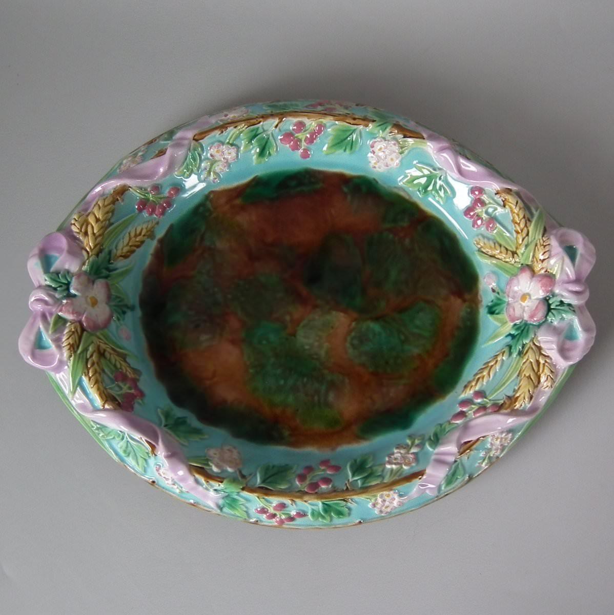 George Jones Majolica bread platter which features hawthorn, ribbon and wheat. Coloration: green, turquoise, pink, are predominant. Bears a pattern number, '1855'.
