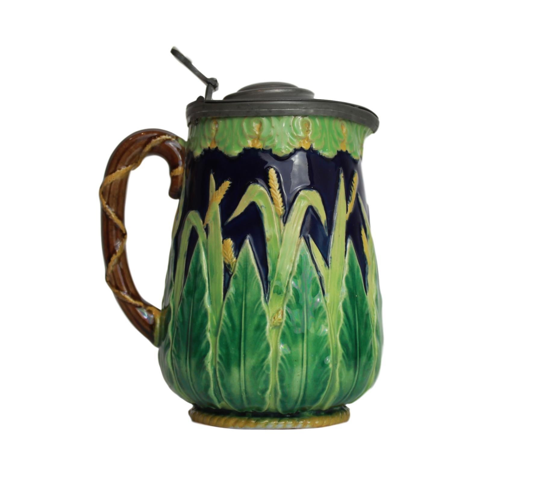George Jones Majolica Cobalt blue wheat pitcher with pewter lid, English circa 1873, the body molded with acanthus leaves glazed in varying shades of green, with naturalistically glazed green and yellow wheat sheaves, with yellow glazed roping to
