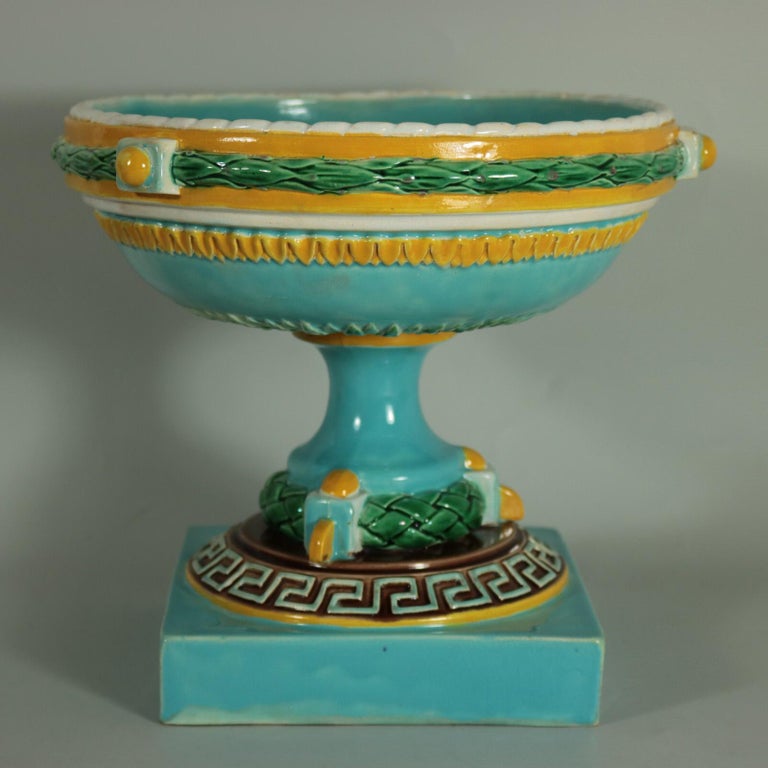 George Jones Majolica compote dish which features geometric patterns and leafy wreaths. Colouration: turquoise, green, ochre, are predominant.