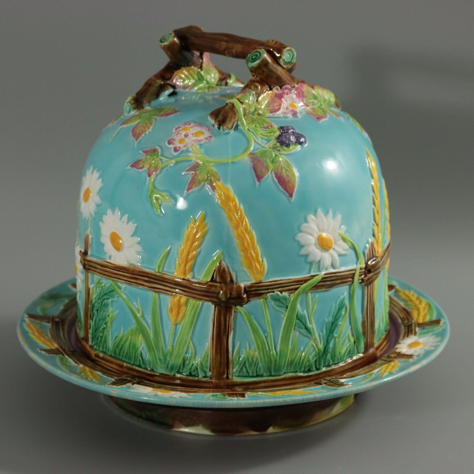 George Jones & Sons Majolica cheese keep which features a picket fence, daisies, corn, brambles and a twig handle. Colouration: turquoise, green, ochre, are predominant. The piece bears maker's marks for the George Jones & Sons pottery. Book