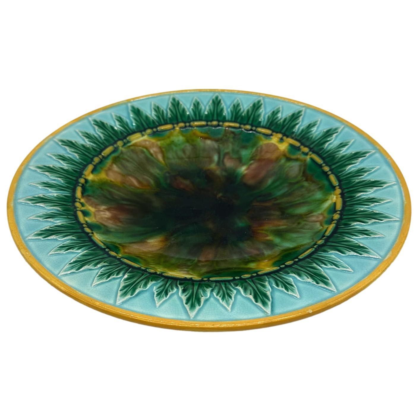 George Jones Majolica Dish, the center with tortoiseshell mottling, bordered with green-glazed acanthus leaves on a turquoise-glazed ground, the inner and outer border rims glazed in yellow ocher, the reverse with impressed 'GJ' monogram and painted