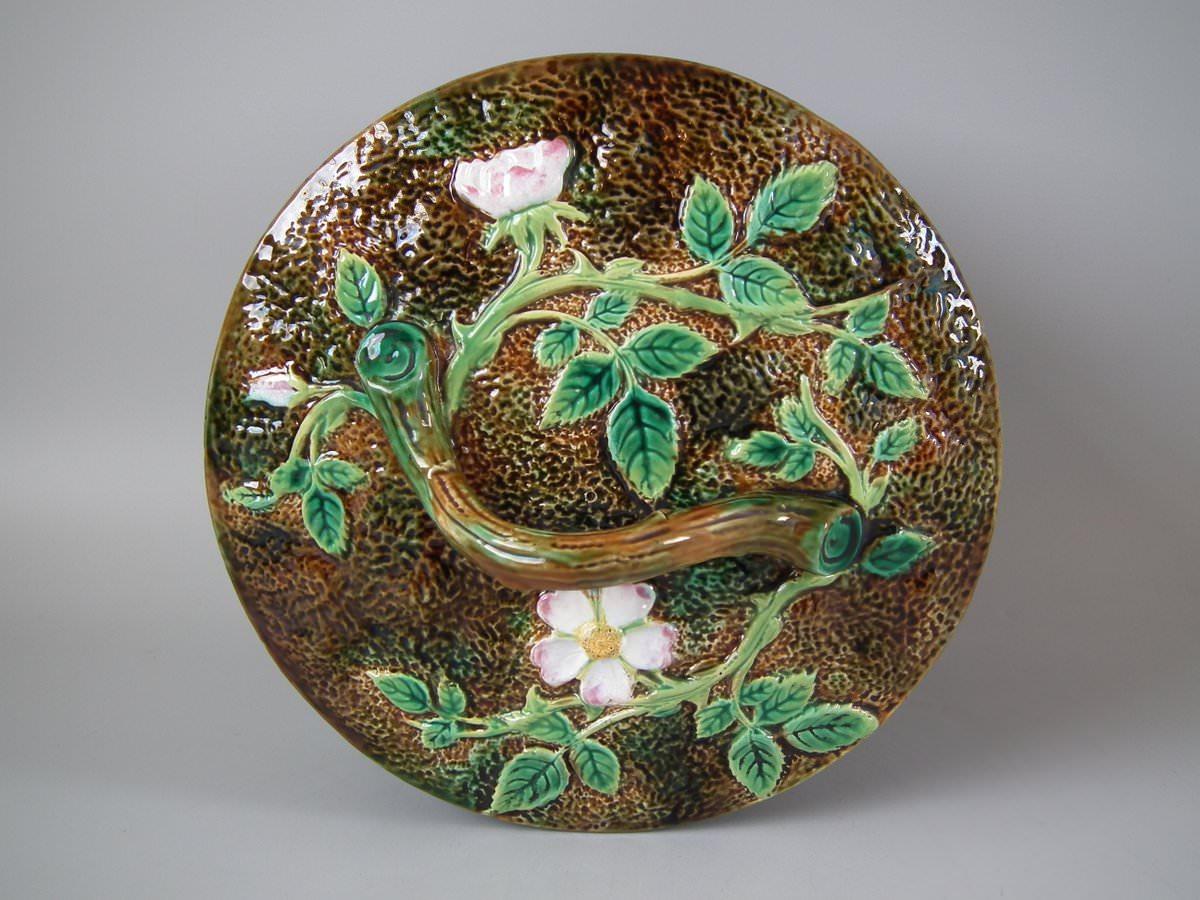George Jones and Sons Majolica cheese keep which features flowering dog rose branches. Coloration: green, pink, brown, are predominant. The piece bears maker's marks for the George Jones and Sons pottery. Bears a pattern number, '3573'.