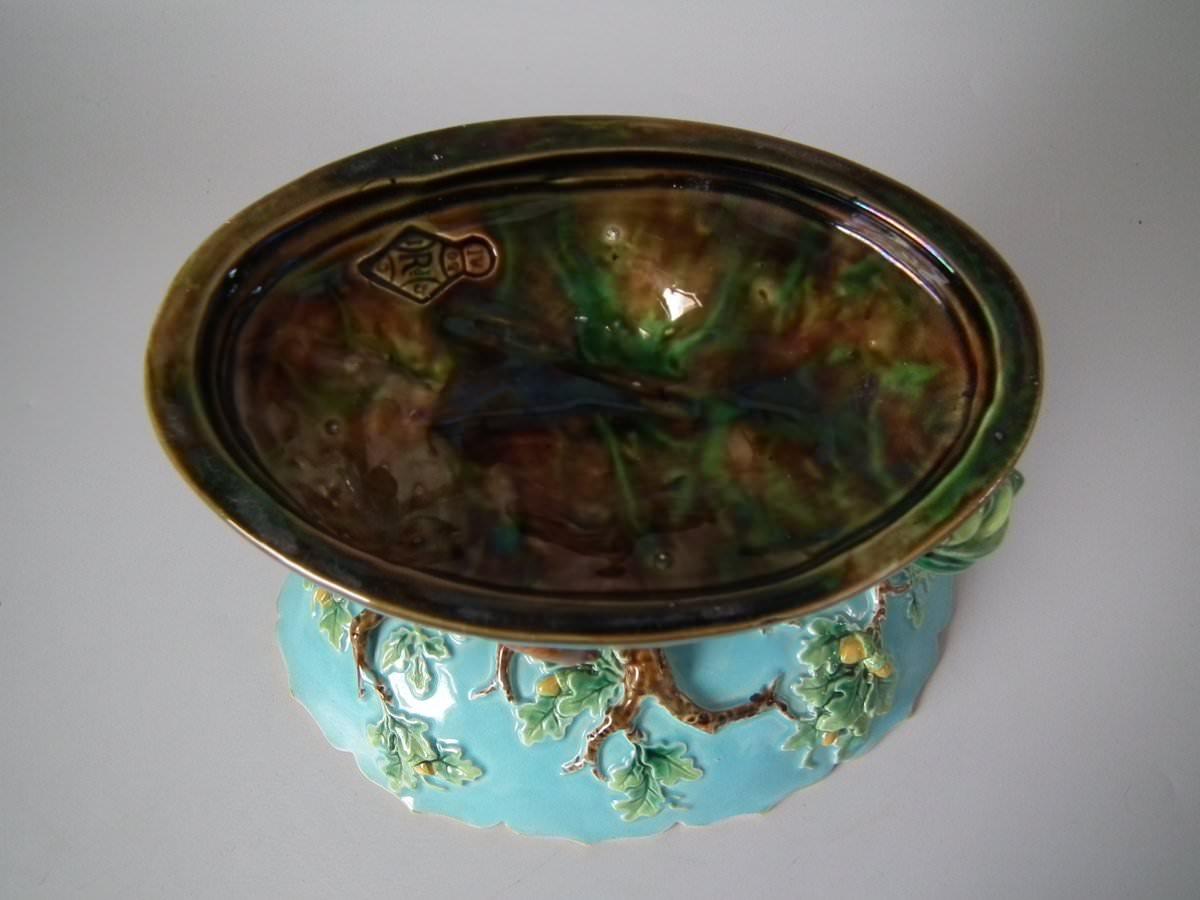 George Jones Majolica compote which features a pointer stalking a bird, underneath and oak tree. Turquoise ground version. Coloration: pink, brown, green, are predominant. English diamond registration mark for the date 02/01/1870. Book