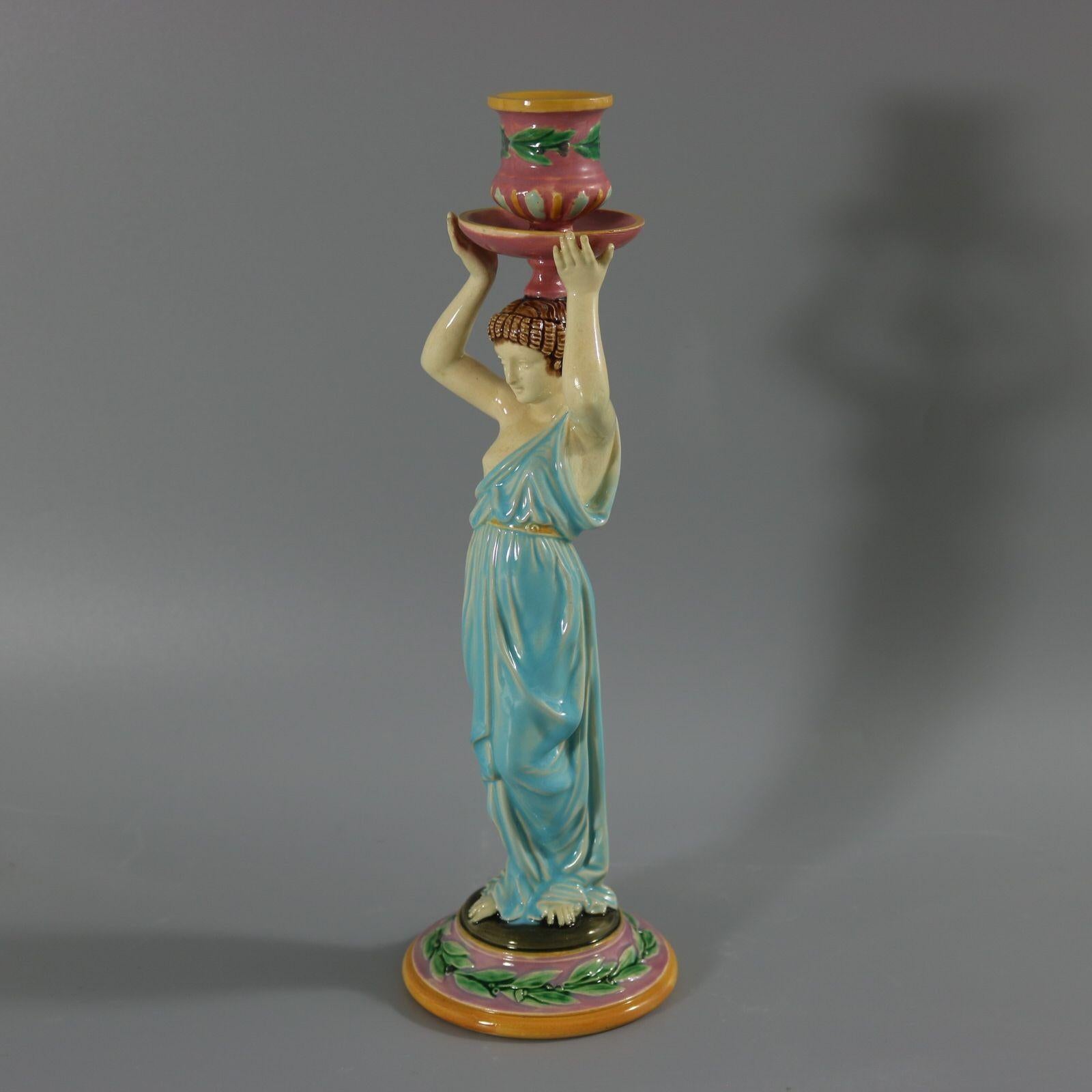 George Jones Majolica candlestick which features a lady dressed in a classical, flowing robe, holding the candle sconce above her head. This piece is one of a few George Jones pieces inspired by Ancient Egypt and the Egyptians. Colouration: