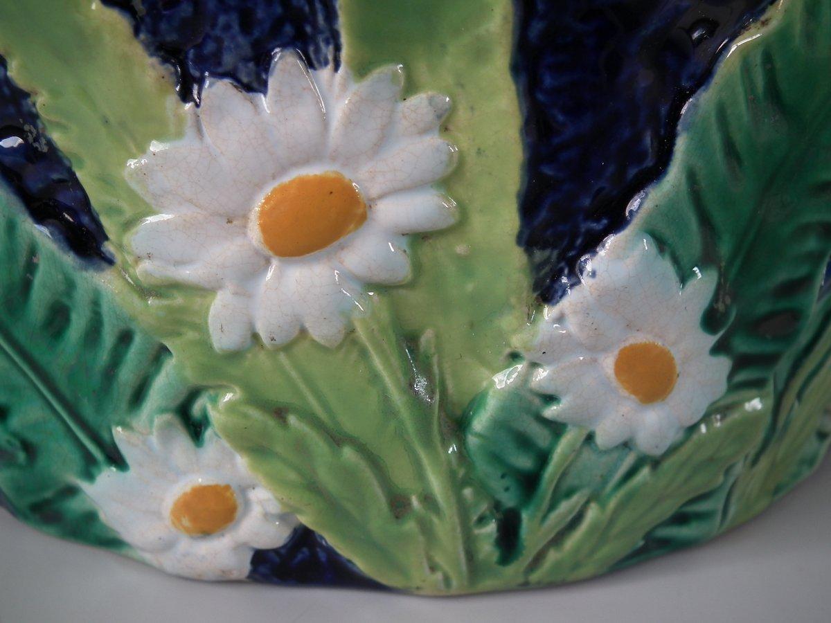 George Jones Majolica cheese keep which features daisy-like flowers and leaves. Cobalt blue ground version. Coloration: Cobalt blue, green, brown, are predominant. The piece bears maker's marks for the George Jones pottery. Bears a pattern number,