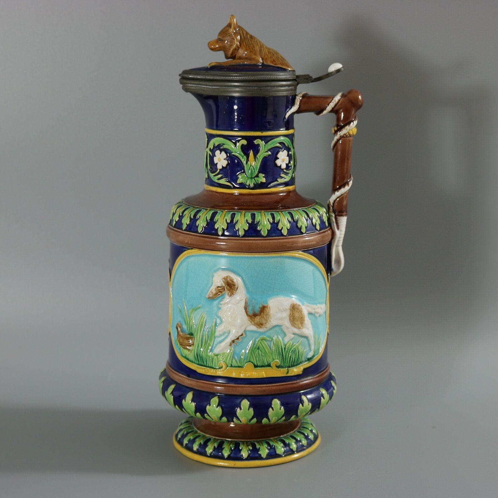George Jones Majolica jug/pitcher with lid which features pictorial panels on either side, one depicts a retriever chasing a quail, the other a fox waiting to pounce on a rabbit. Colouration: turquoise, blue, green, are predominant. English diamond