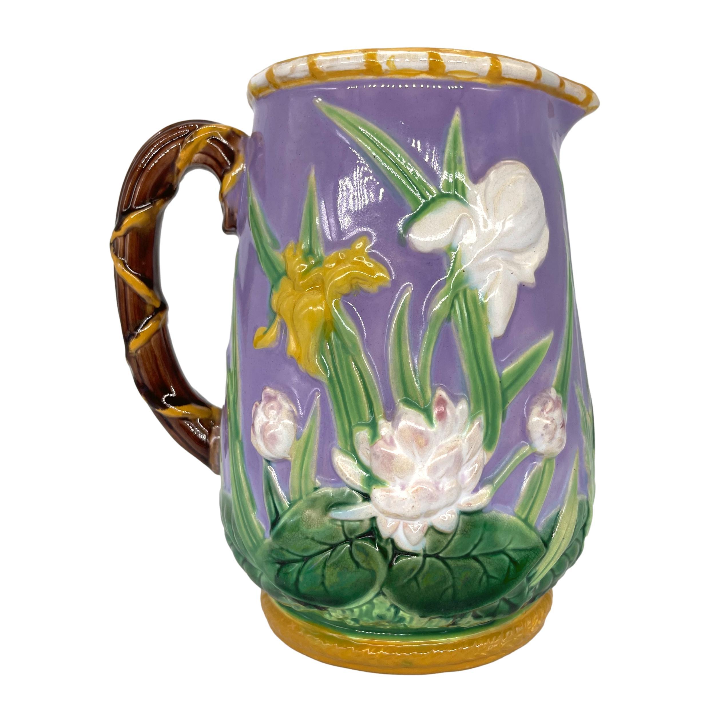 George Jones Majolica Pitcher with Relief-Molded Irises, Daffodils, and Water-Lilies, the branch-form handle, top rim, and spout banded in yellow, on raised back with yellow-glazed roping, the interior glazed in pink, the reverse heavily glazed in