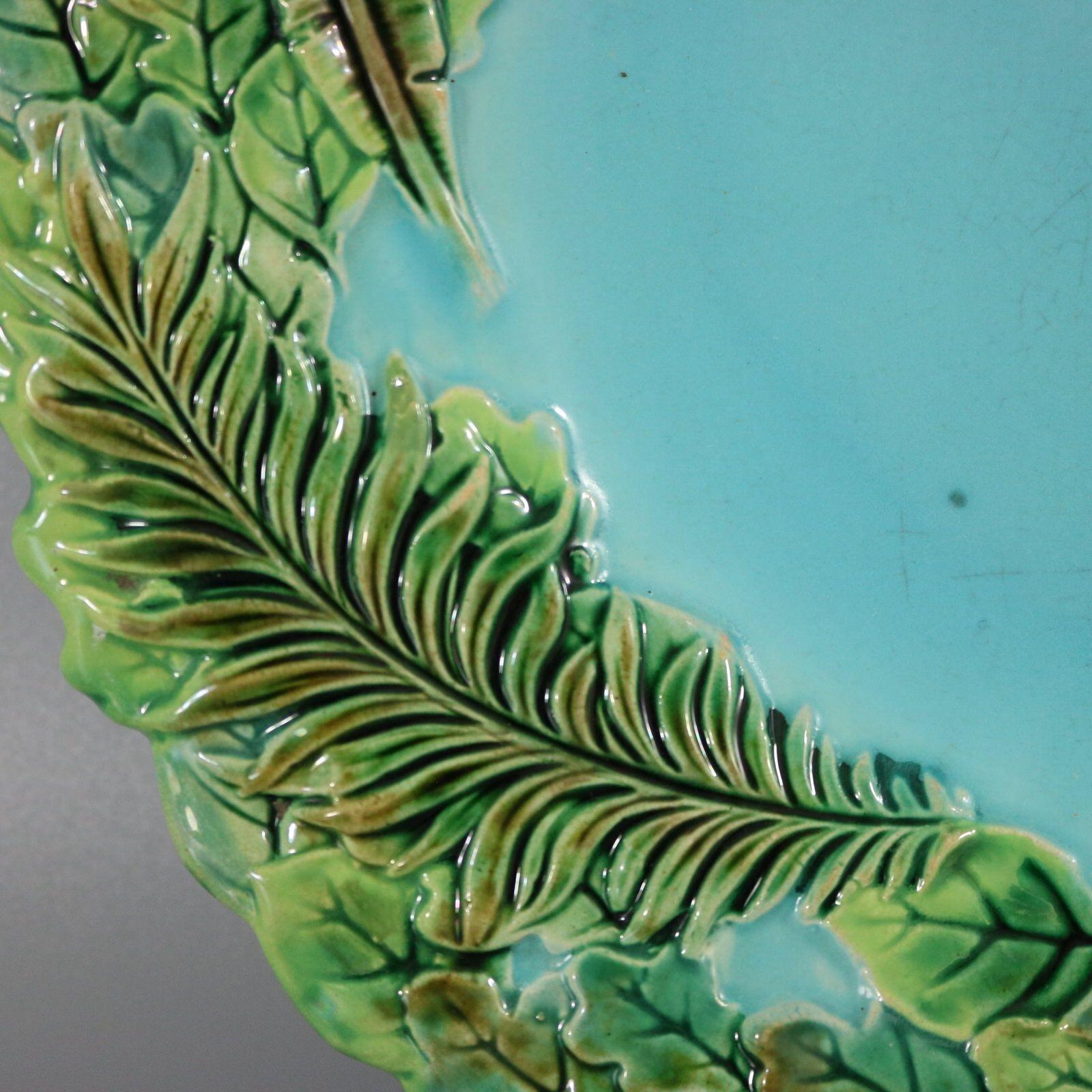George Jones Majolica plate which features jungle plant leaves and ferns. Colouration: turquoise and green are predominant. Bears a pattern number, '3230'.