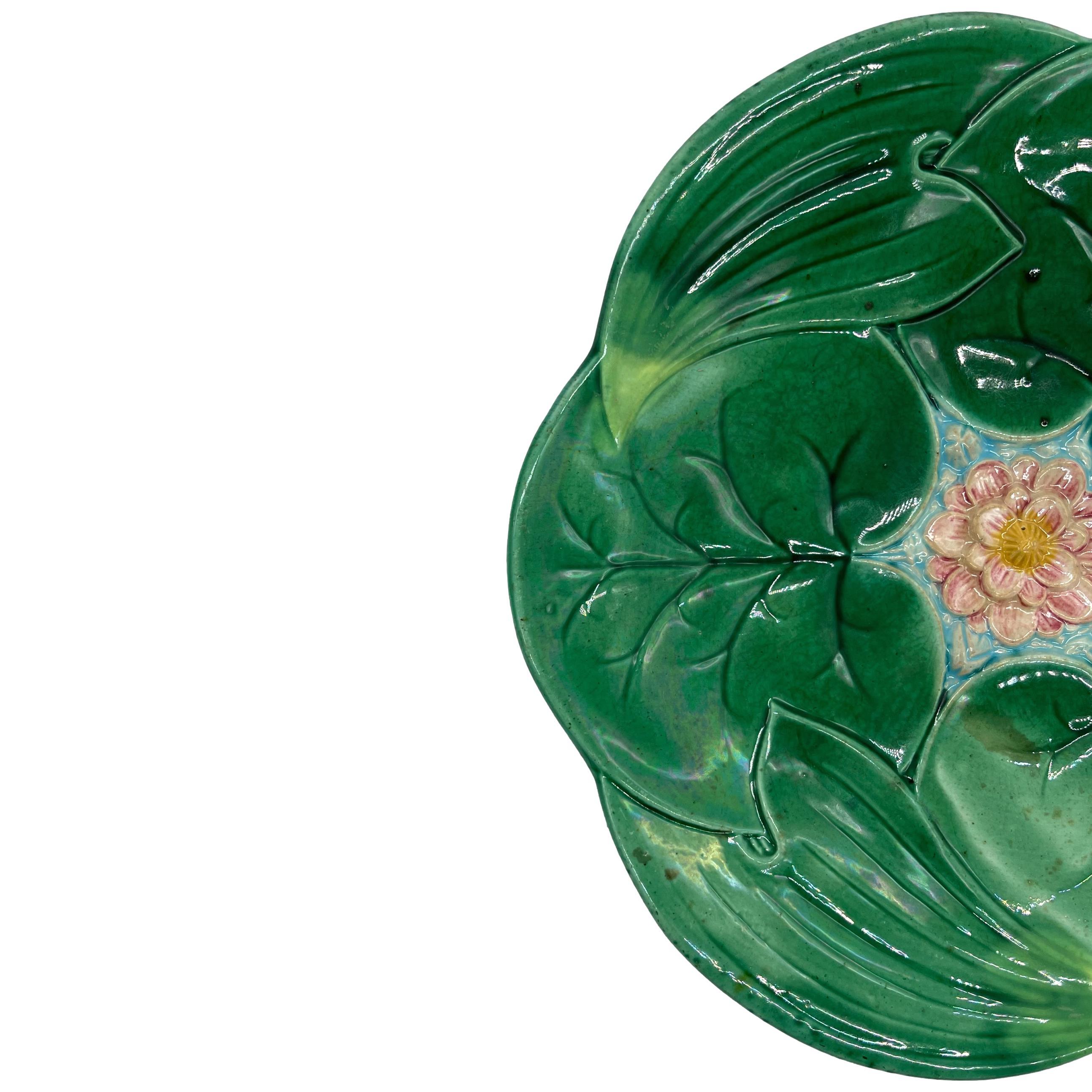 Assiette à lotus en majolique de George Jones, moulée de façon naturaliste comme des nénuphars et des feuilles de lotus se chevauchant, avec une fleur de lotus centrale rose et jaune moulée en relief sur de l'eau émaillée turquoise, le revers