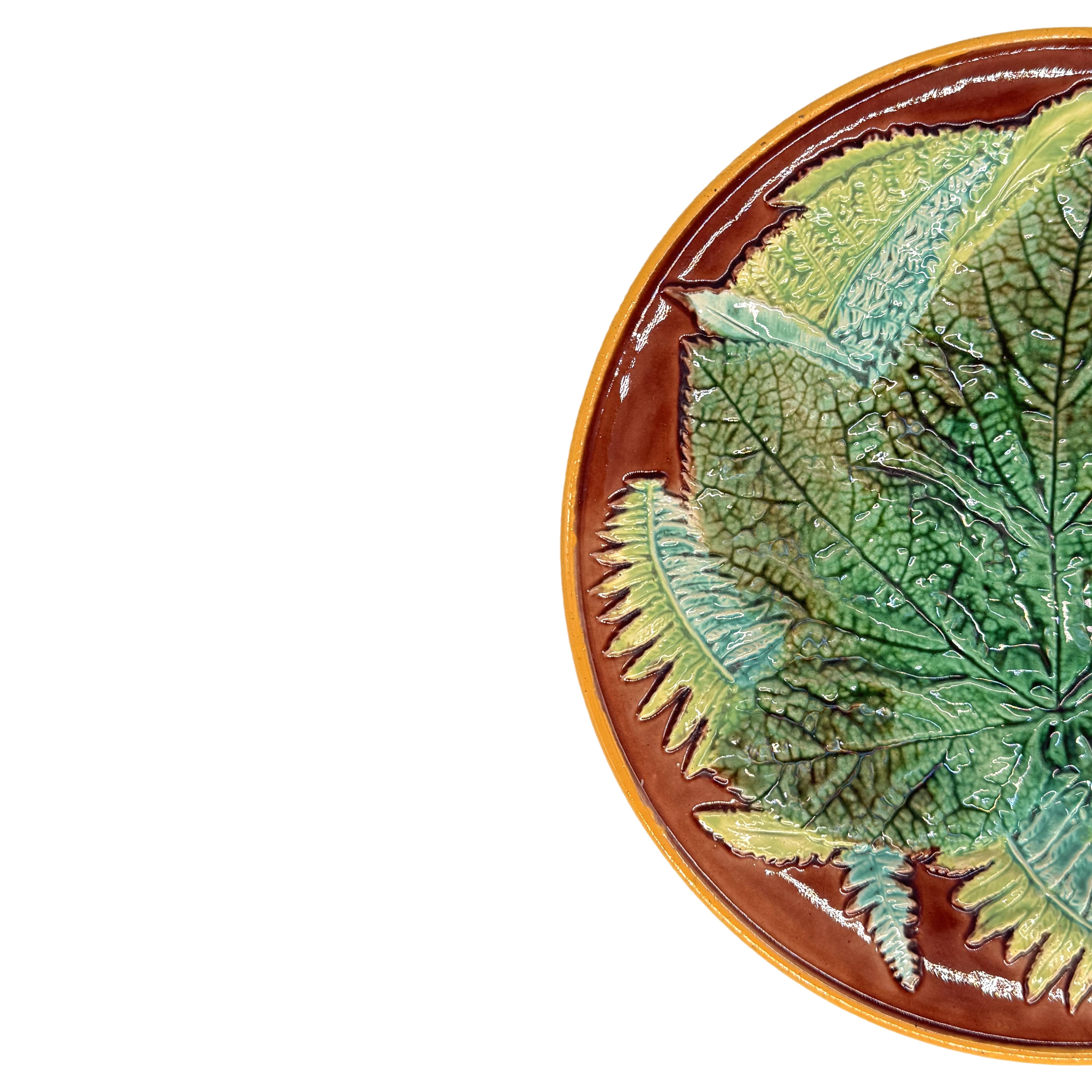 Plato de hoja de arce y helechos de George Jones Majolica, inglés, hacia 1870, plato moldeado en relieve con una hoja de arce central esmaltada en verde con helechos sobre fondo marrón, borde con bandas de ocre amarillo, reverso esmaltado con