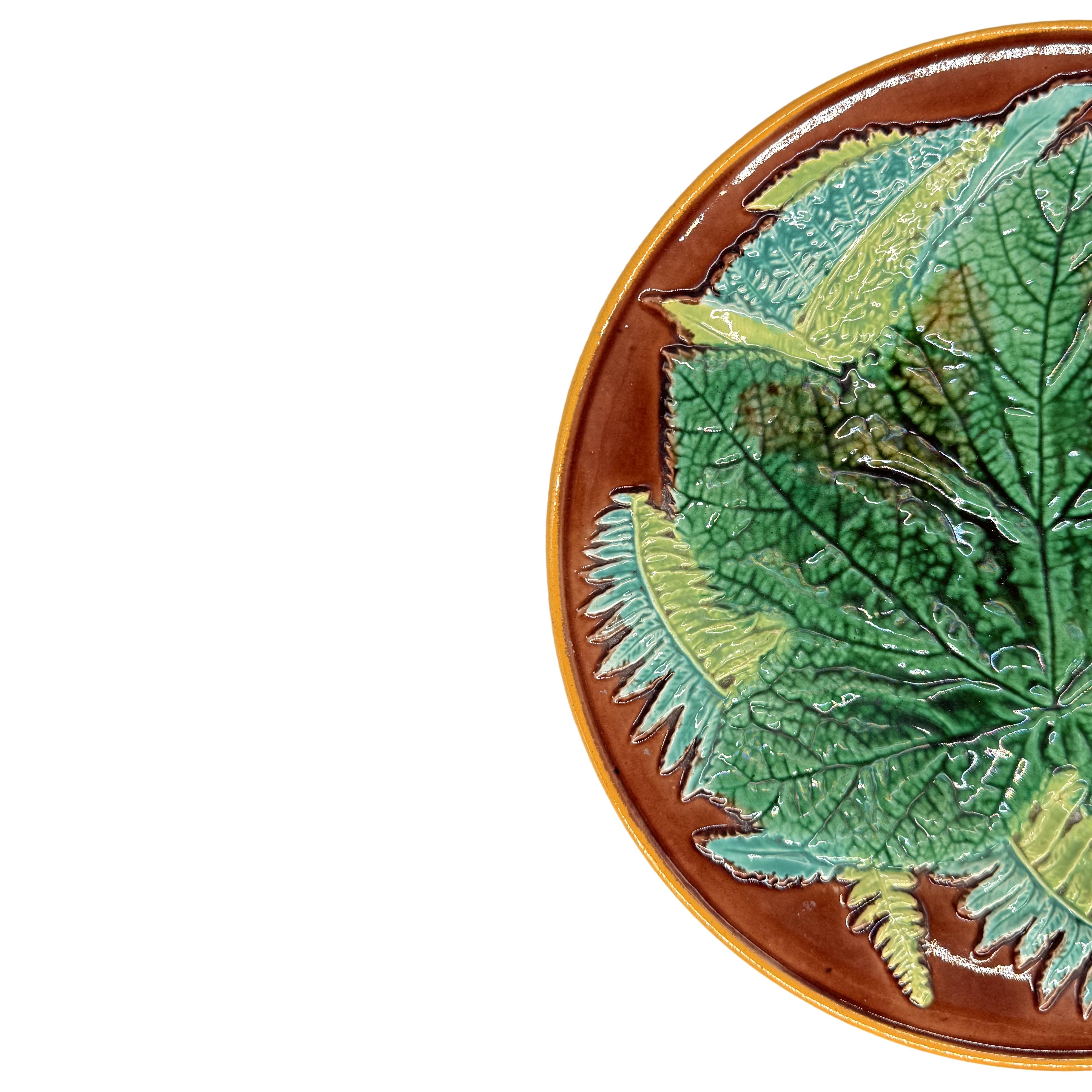 Piatto in maiolica con foglie d'acero e felci di George Jones, inglese, 1870 ca. 1870, il piatto modellato a rilievo con una foglia d'acero centrale smaltata in verde con felci su fondo marrone, il bordo bordato in giallo ocra, il rovescio smaltato