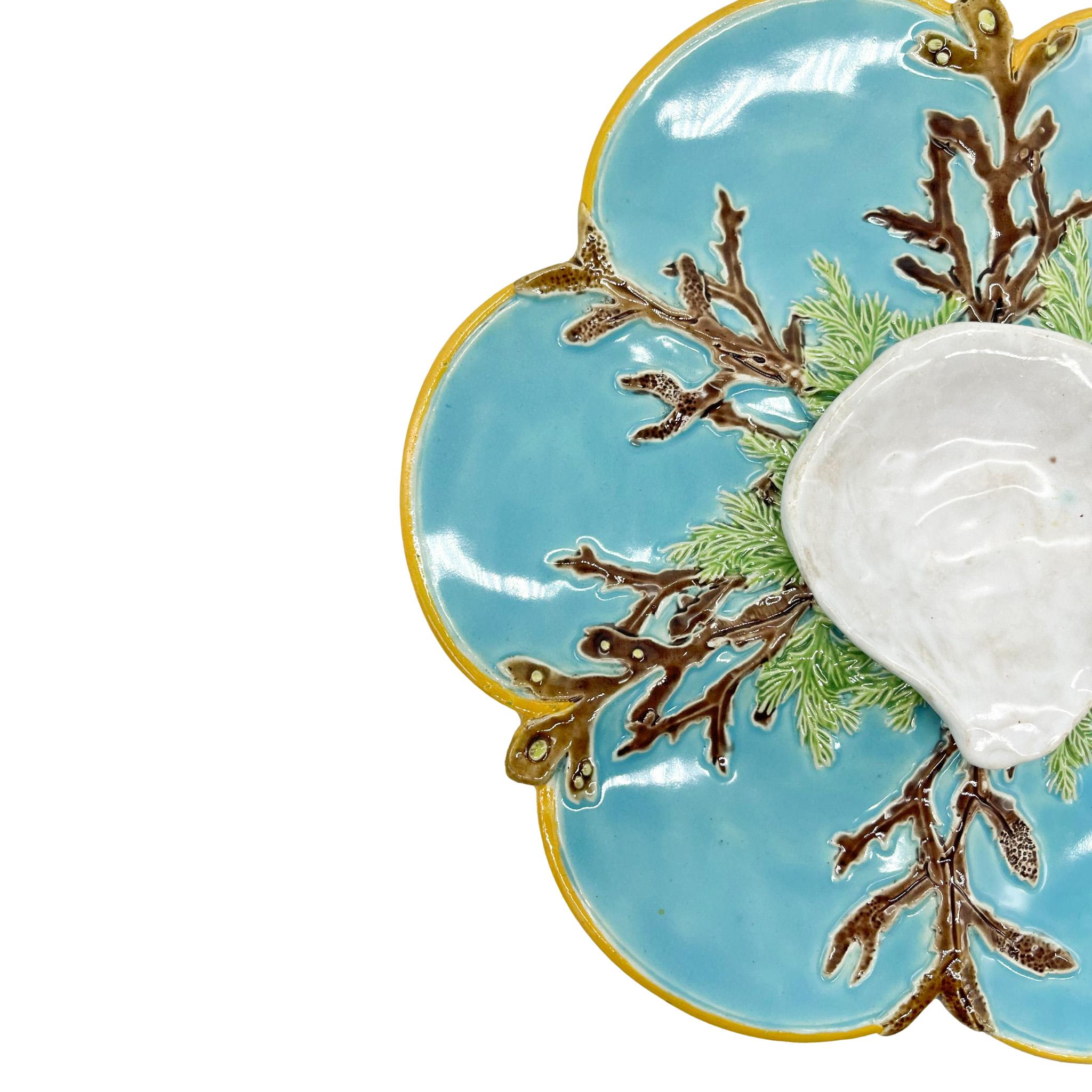 George Jones Majolica Oyster Dish, the six turquoise-glazed wells separated by coral tentacles, the central dipping well naturalistically molded as an oyster half-shell applied on a bed of green-glazed seaweed, with a yellow ocher rim; the reverse