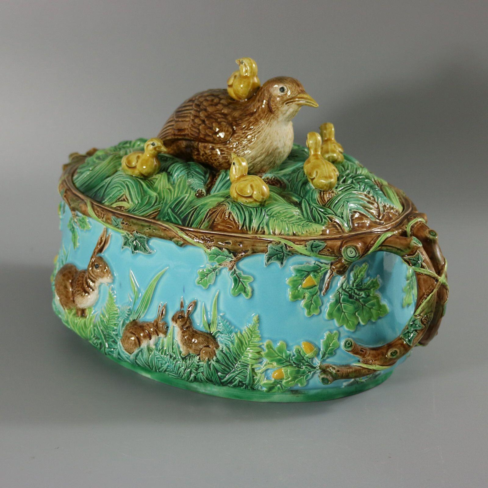 George Jones Majolica game pie dish which features features a partridge on a nest of grasses and ferns, with seven chicks. One chick is sat on its mother's back, and another is tucked under her wing. The dish with grazing rabbits to the sides.