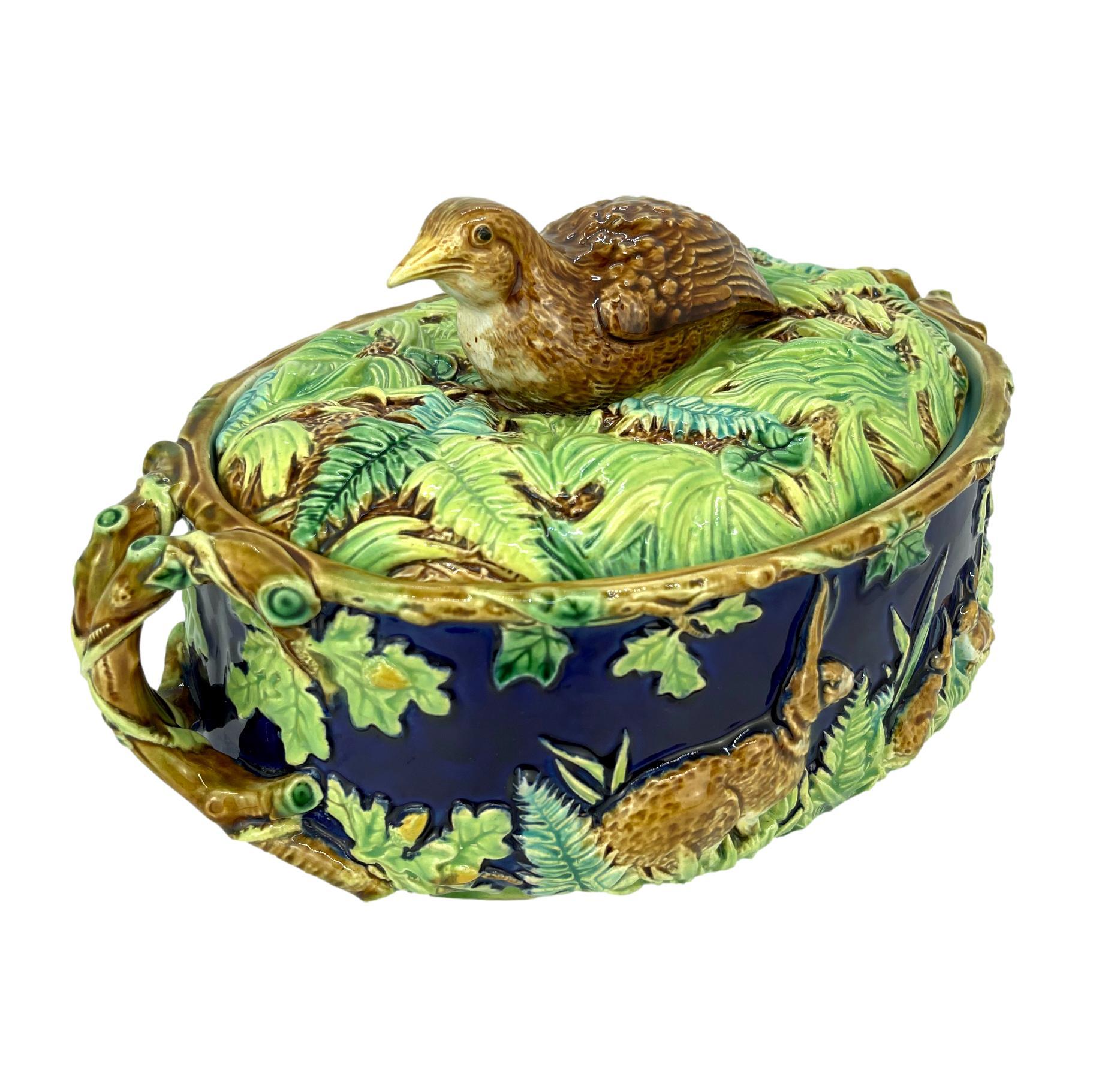 George Jones Majolica Partridge Tureen/Game Pie dish, molded with a single partridge nesting among grasses forming the knop, the dish with relief-molded rabbits among green-glazed ferns, grasses, and oak leaves with yellow acorns on a cobalt blue